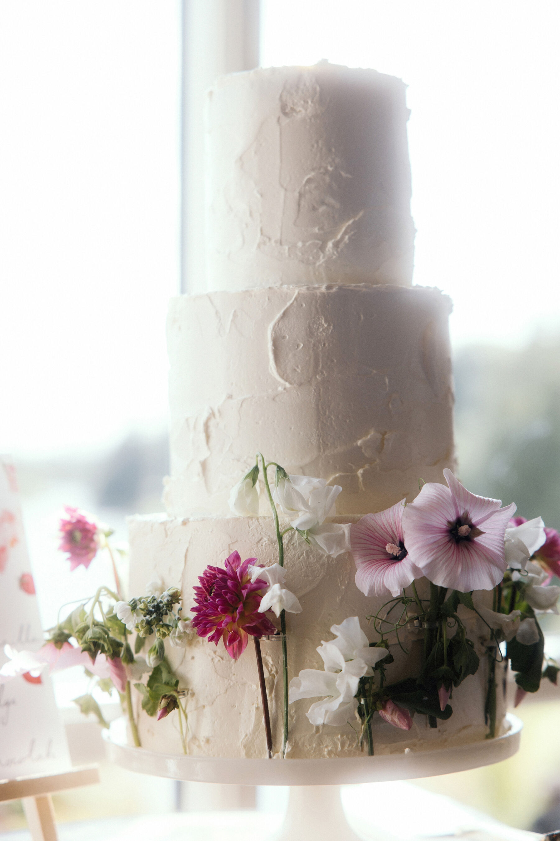 Romantic Ballynahinch Castle Wedding: Ciara in Danielle Frankel 35 3 tier simple wedding cake with the bottom tier decorated with fresh flowers.