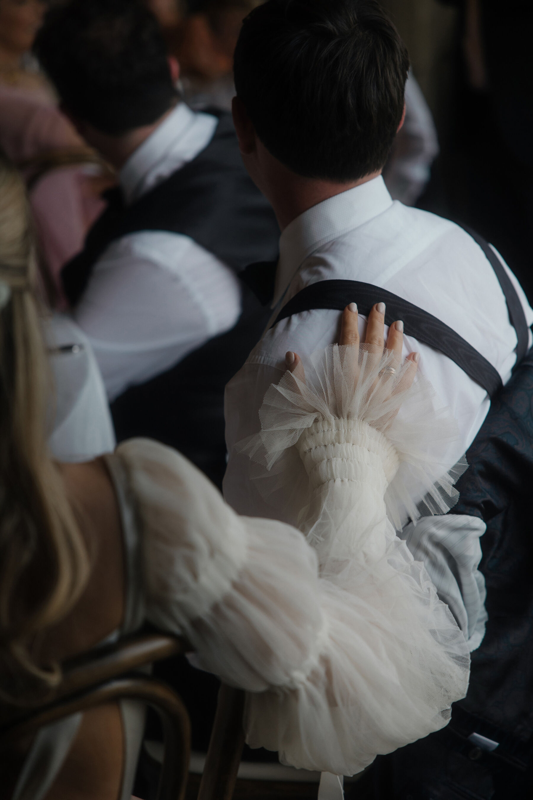 Romantic Ballynahinch Castle Wedding: Ciara in Danielle Frankel 36 A bride in a Danielle Frankel wedding dress holding on to the shoulder of her groom in braces.