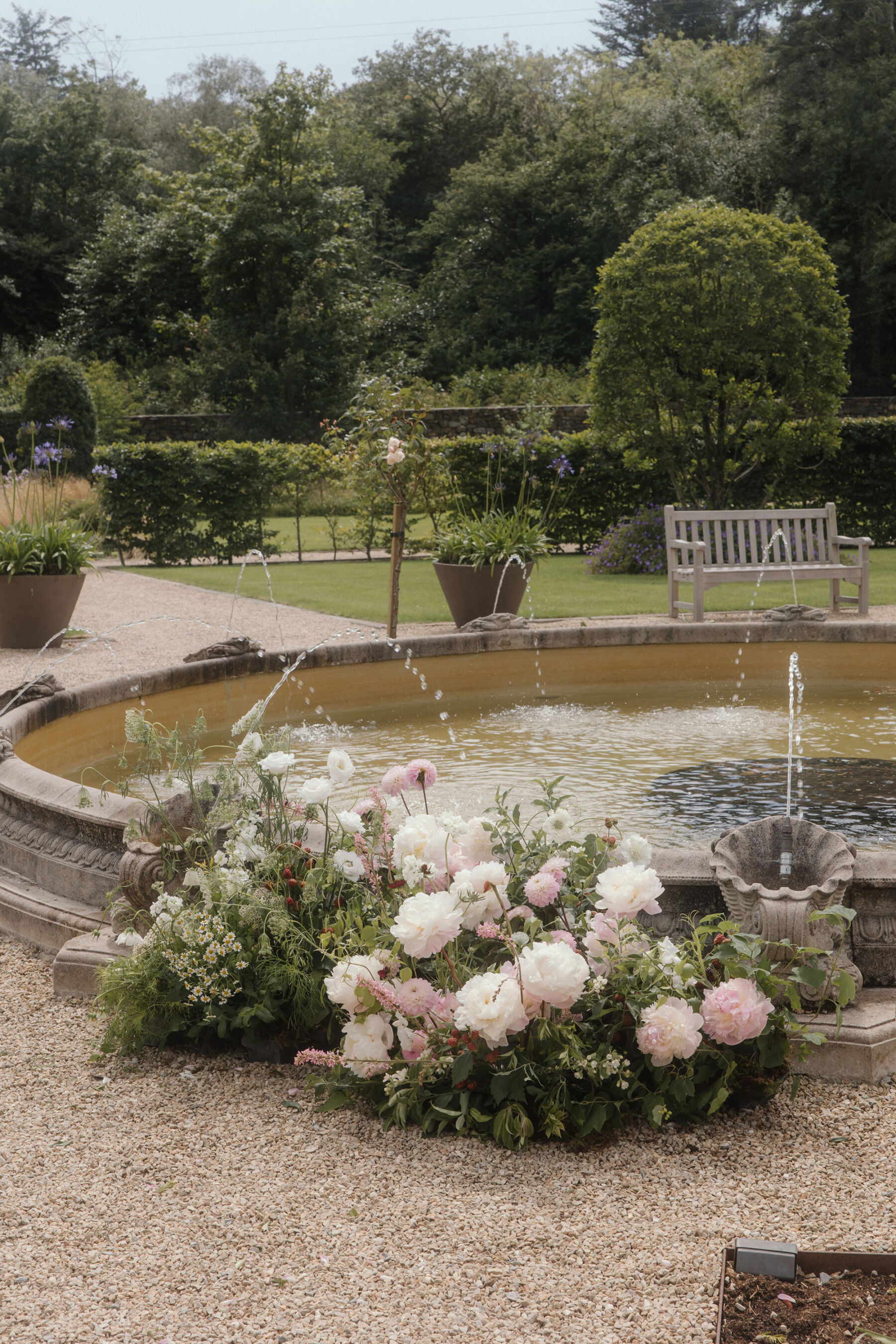 Romantic Ballynahinch Castle Wedding: Ciara in Danielle Frankel 22 Low floral display by a water fountain in the gardens at Ballynahinch Castle in Ireland.