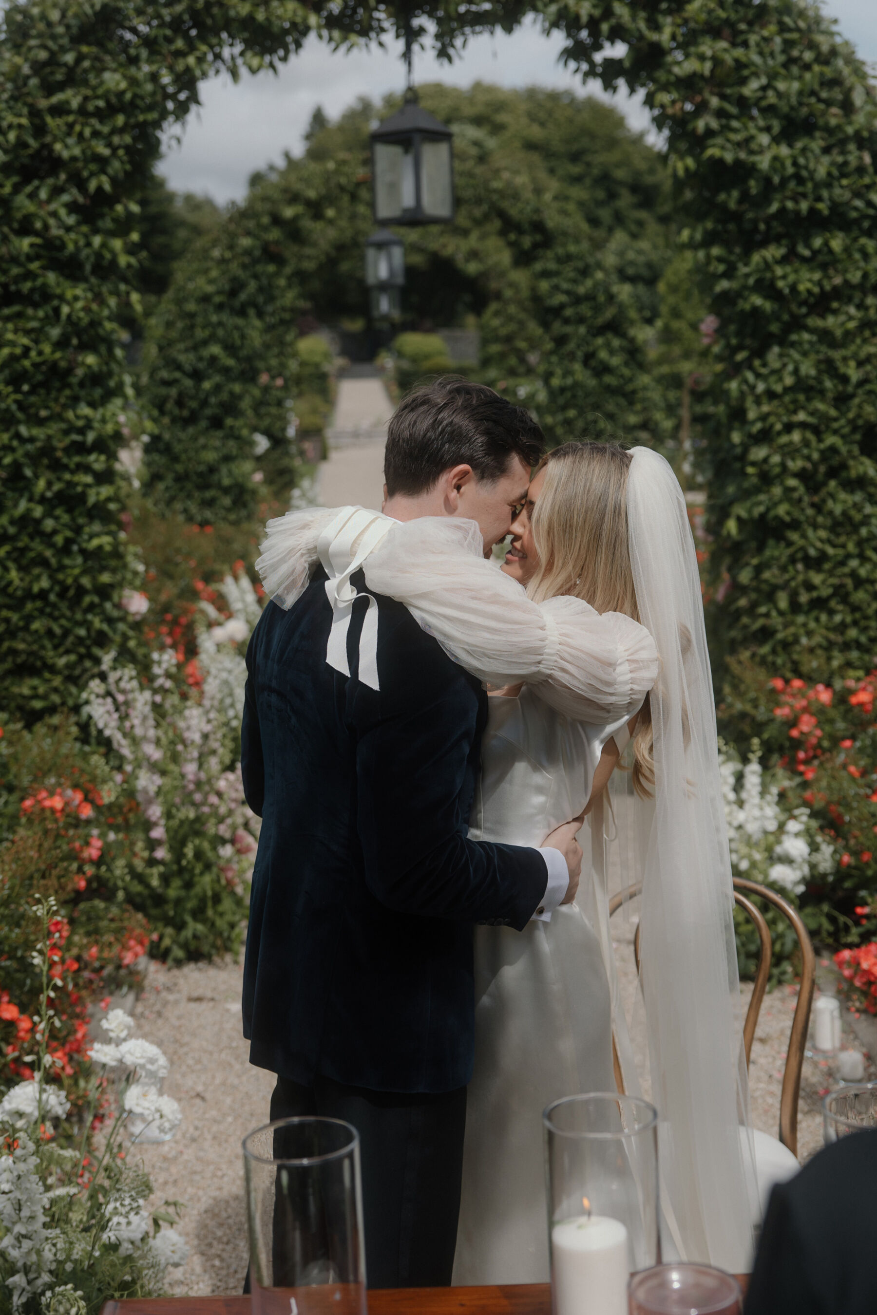 Romantic Ballynahinch Castle Wedding: Ciara in Danielle Frankel 21 Outdoor wedding, bride in a Danielle Frankel wedding dress holds her husband around the shoulder as he holds her around the waist.