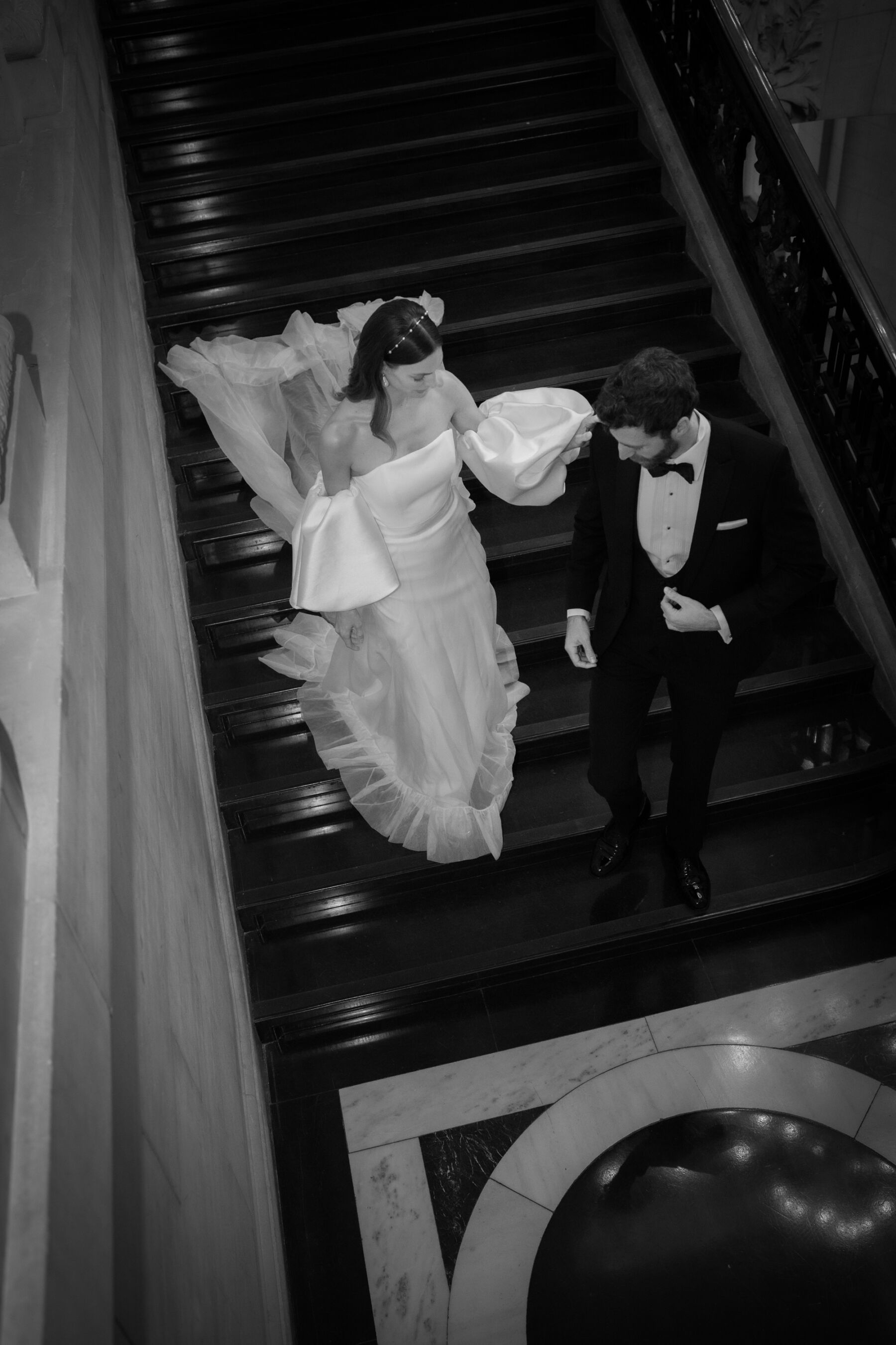 Modern bride in Halfpenny London dress descending the stairs with her groom in black tie, at 10-11 Carlton Terrace London. Car Arwel Photography.