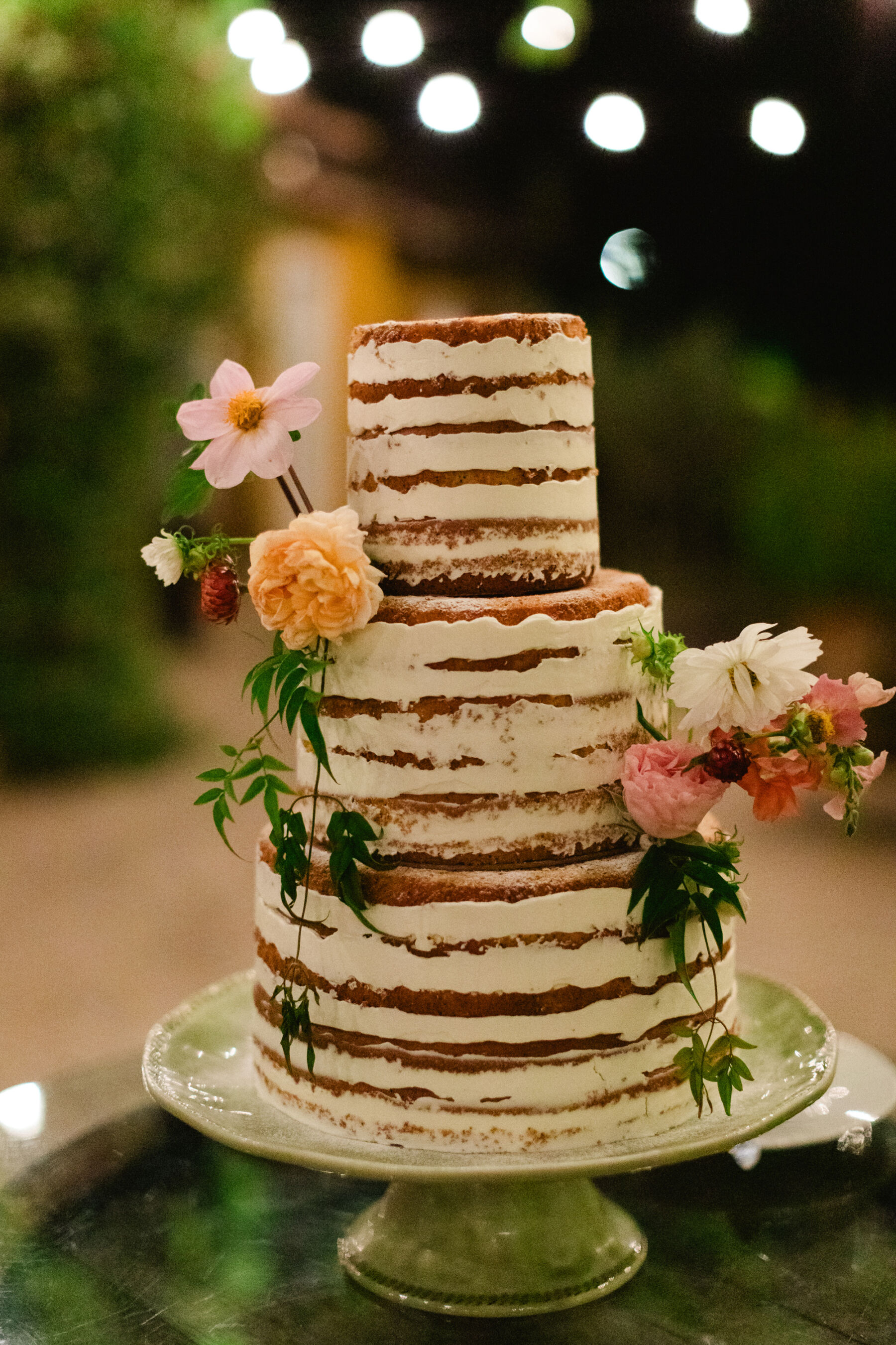 Olivia & Tim's Classy & Elegant Vineyard Wedding in Portugal 42 3 tier naked cake with flowers on a green porcelain cake stand.
