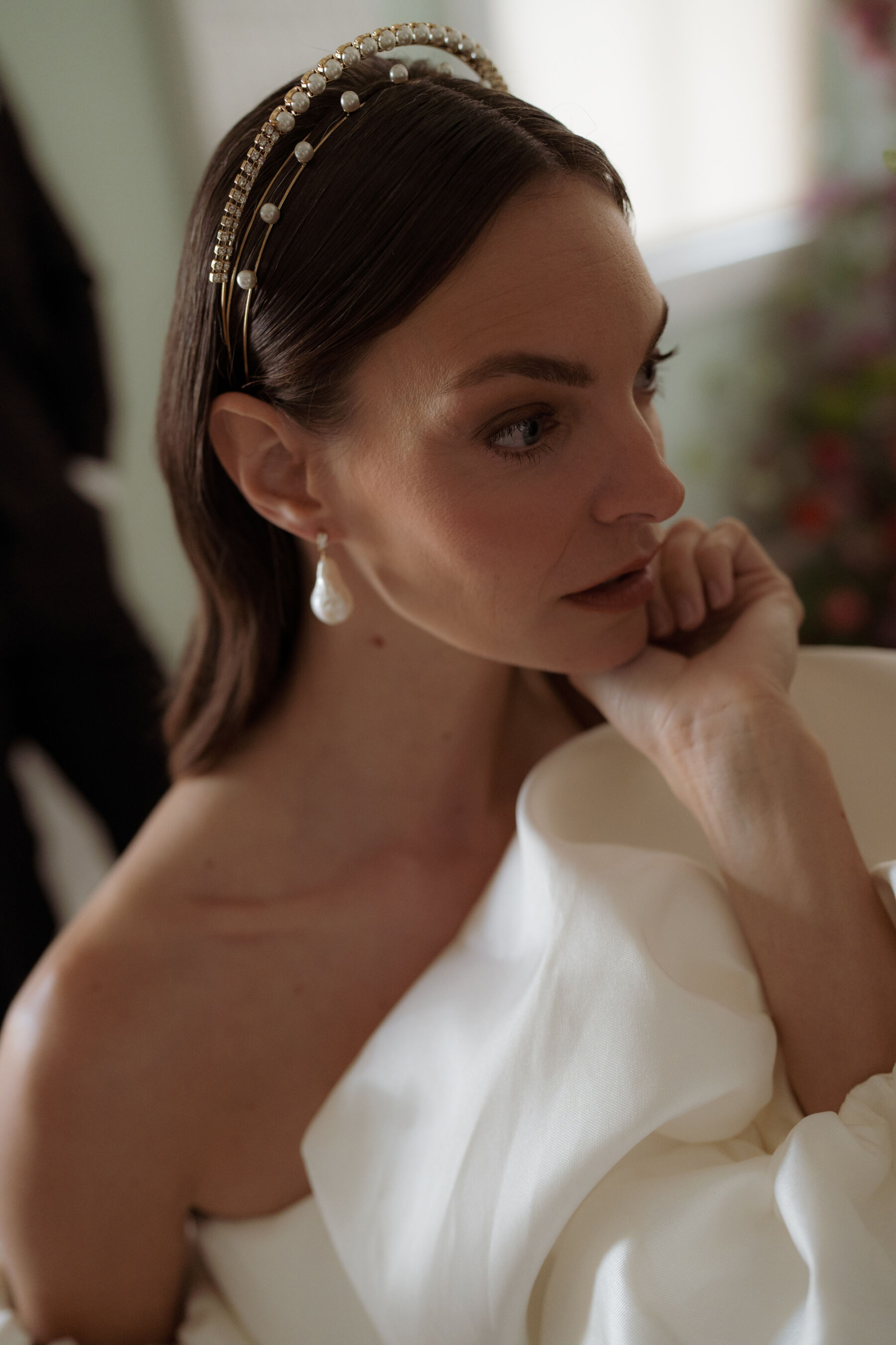 Bride wearing Tilly Thomas Lux headpieces and pearl drop earrings shaped like pears.