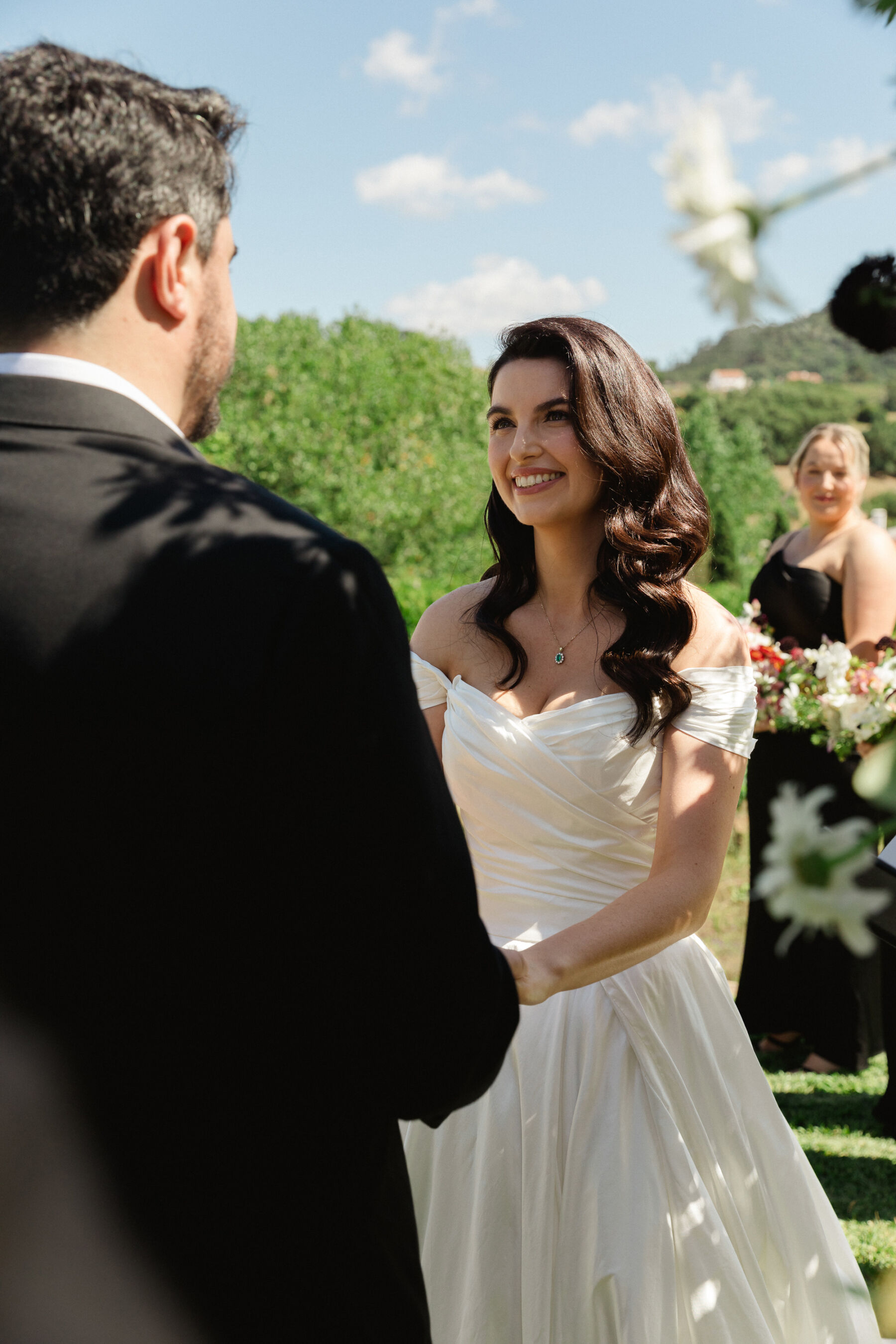 Olivia & Tim's Classy & Elegant Vineyard Wedding in Portugal 26 Bride with marcel waves in her hair holding her groom's hand during their outdoor wedding ceremony and staring lovingly into his eyes.