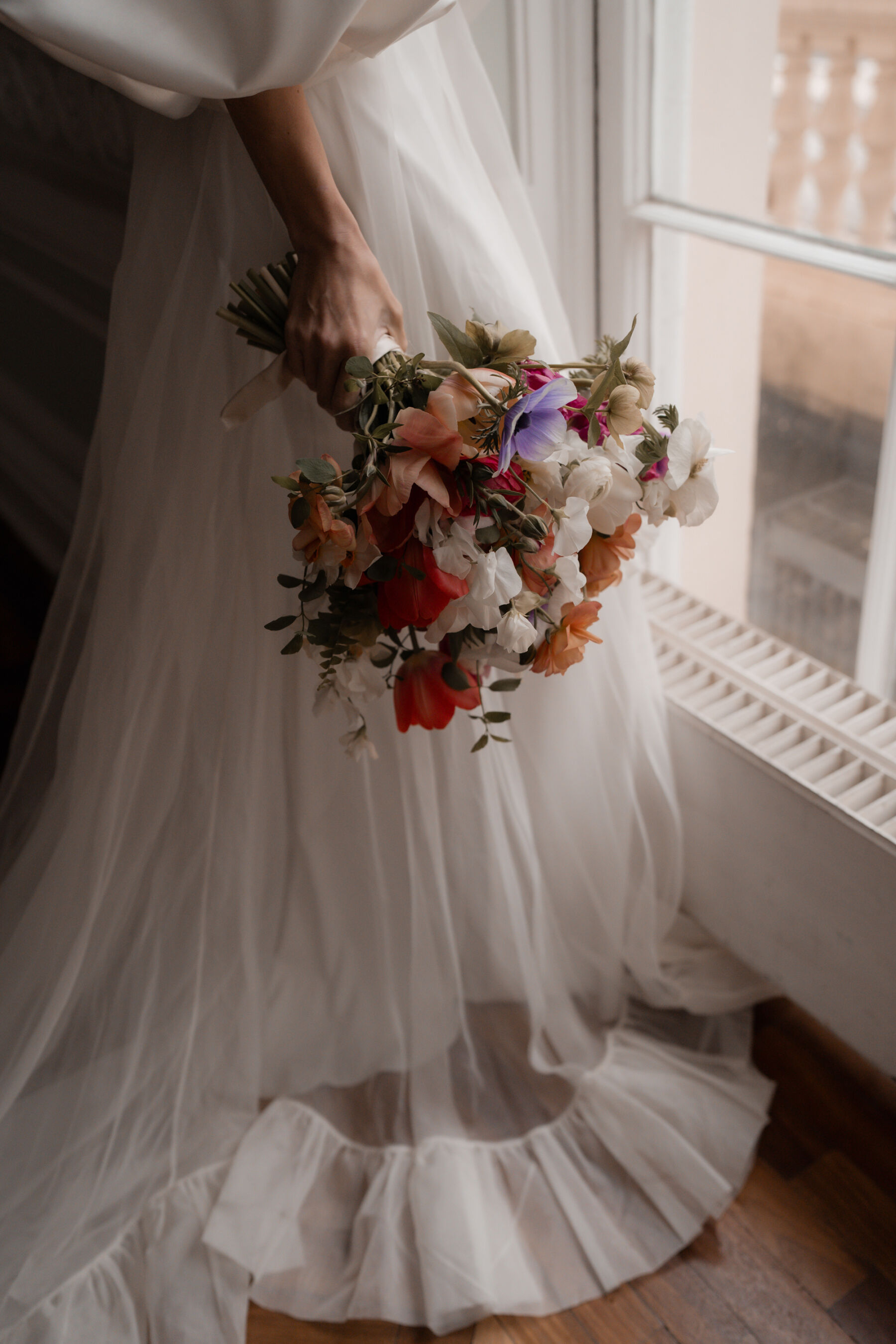 Close up of a bride wearing a Halfpenny London wedding dress, and holding a colourful Spring bouquet of Icelandic Poppies.