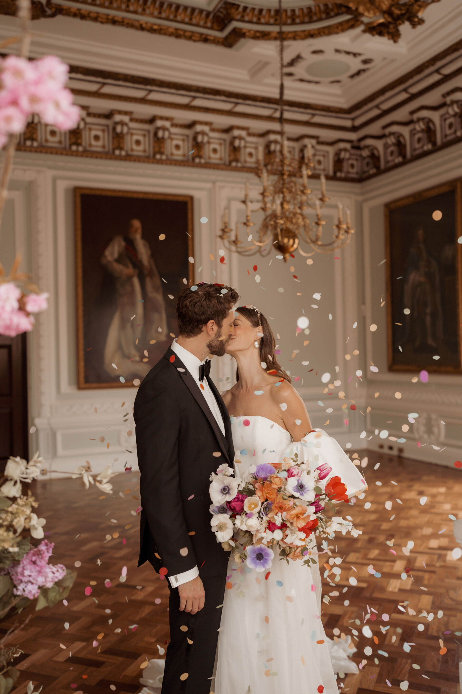 Bride and groom getting showered in colourful paper confetti inside 10-11 Carlton Terrace London. 