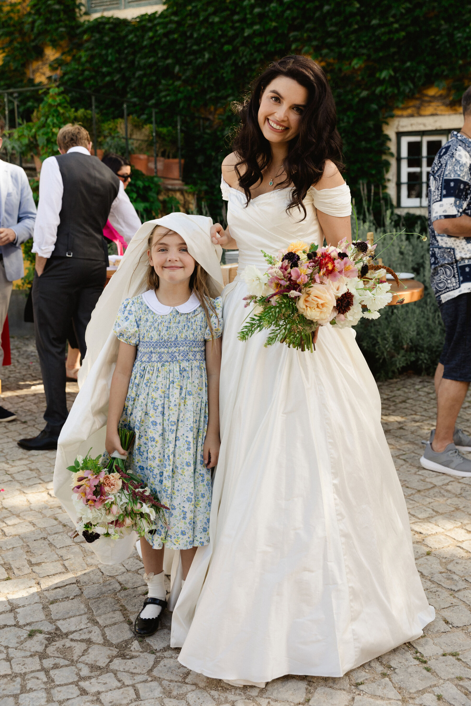 Olivia & Tim's Classy & Elegant Vineyard Wedding in Portugal 28 Cute photograph of a bride with the train of her wedding dress over the top of the flowergirls head. Flowergirl in a Peter Pan collar dress.