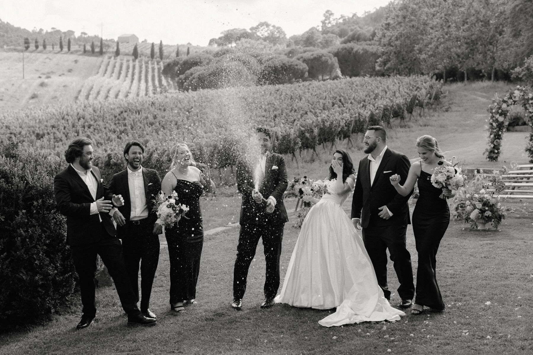 Olivia & Tim's Classy & Elegant Vineyard Wedding in Portugal 31 Bride and groom in Portugal popping a bottle of champagne with the bridesmaids and groomsmen.