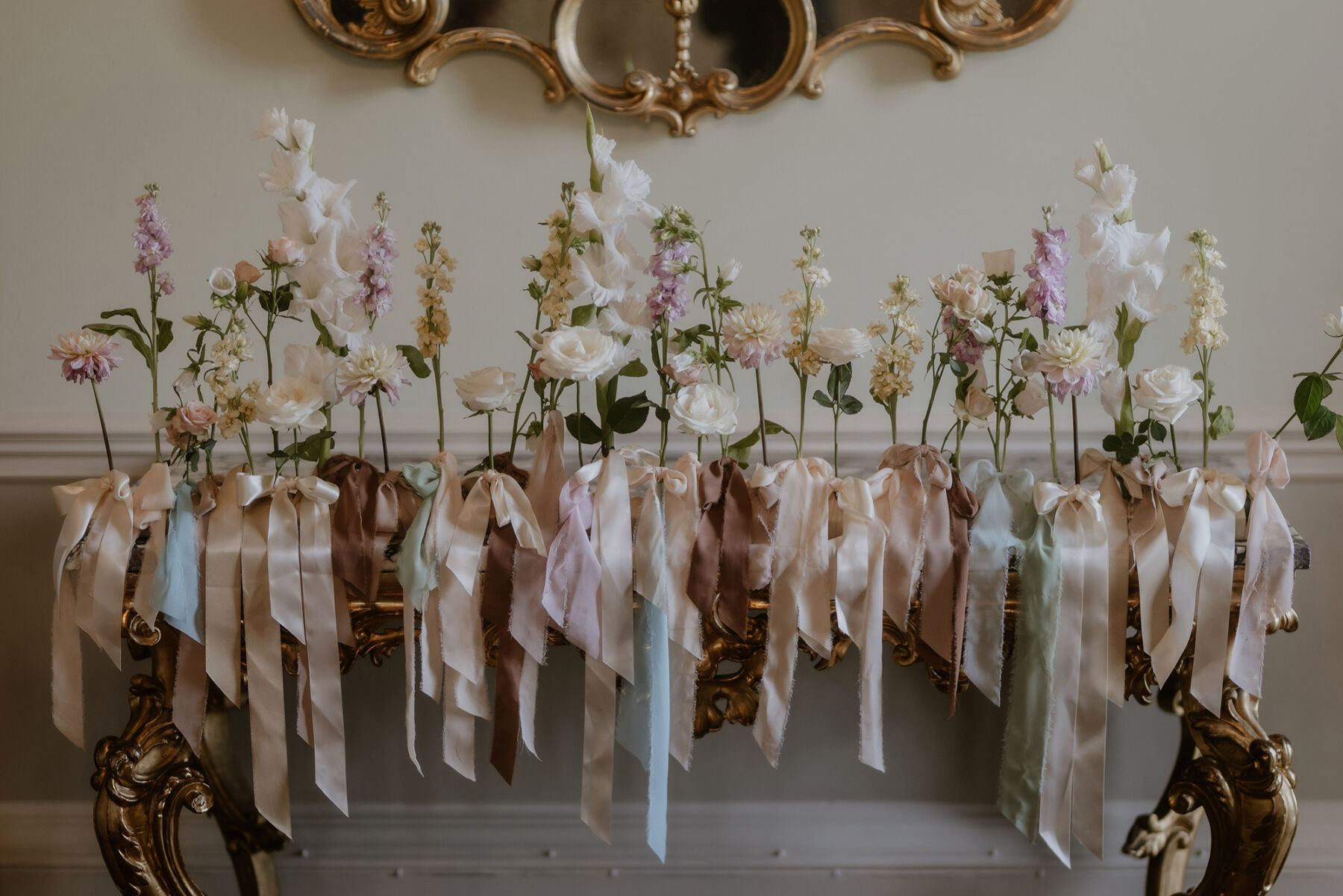 An Investment Banker & Her Prestwold Hall Wedding, with a Milla Nova Gown & Berta Legging Boots 32 Single stem flowers on top of a fireplace, with pastel silk ribbons tied around the stem.