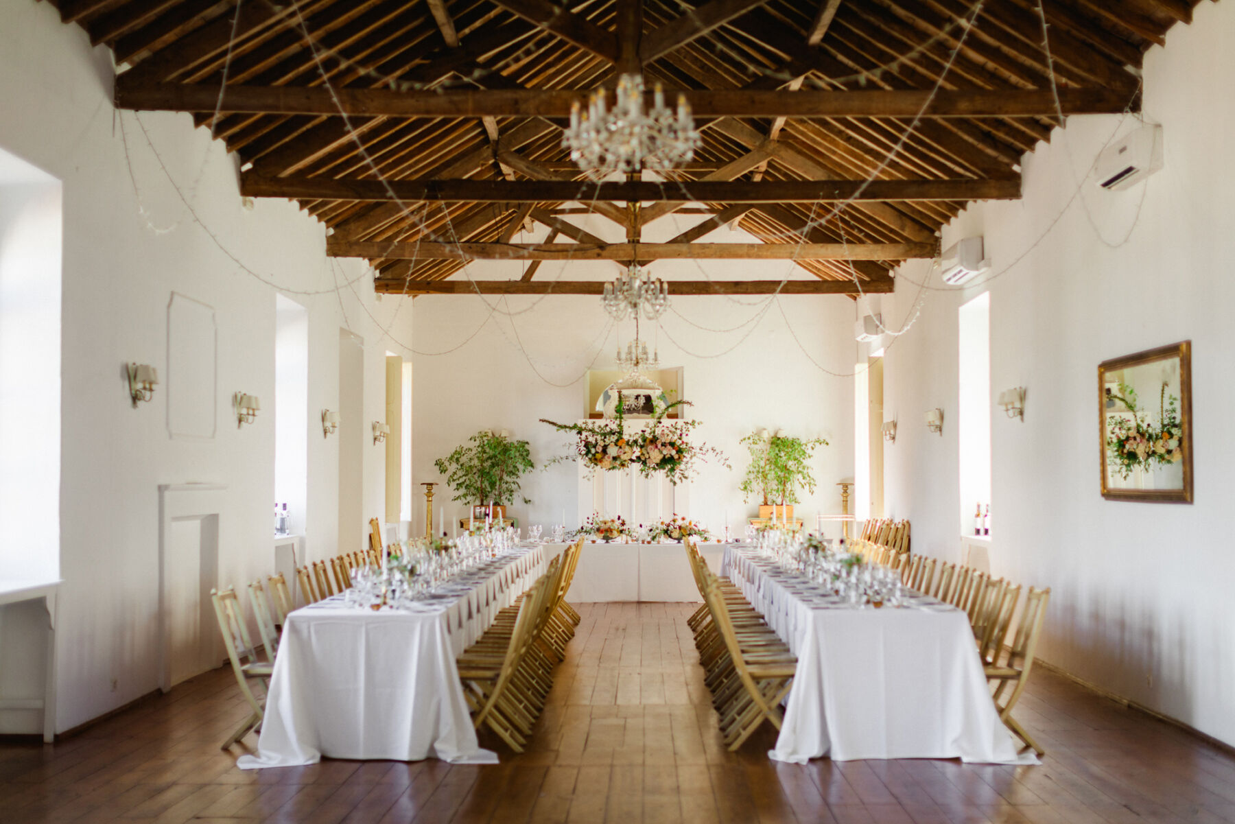 Olivia & Tim's Classy & Elegant Vineyard Wedding in Portugal 37 Elegant converted barn wedding reception with 2 rows of long trestle tables covered in white table cloths and a separate top table.