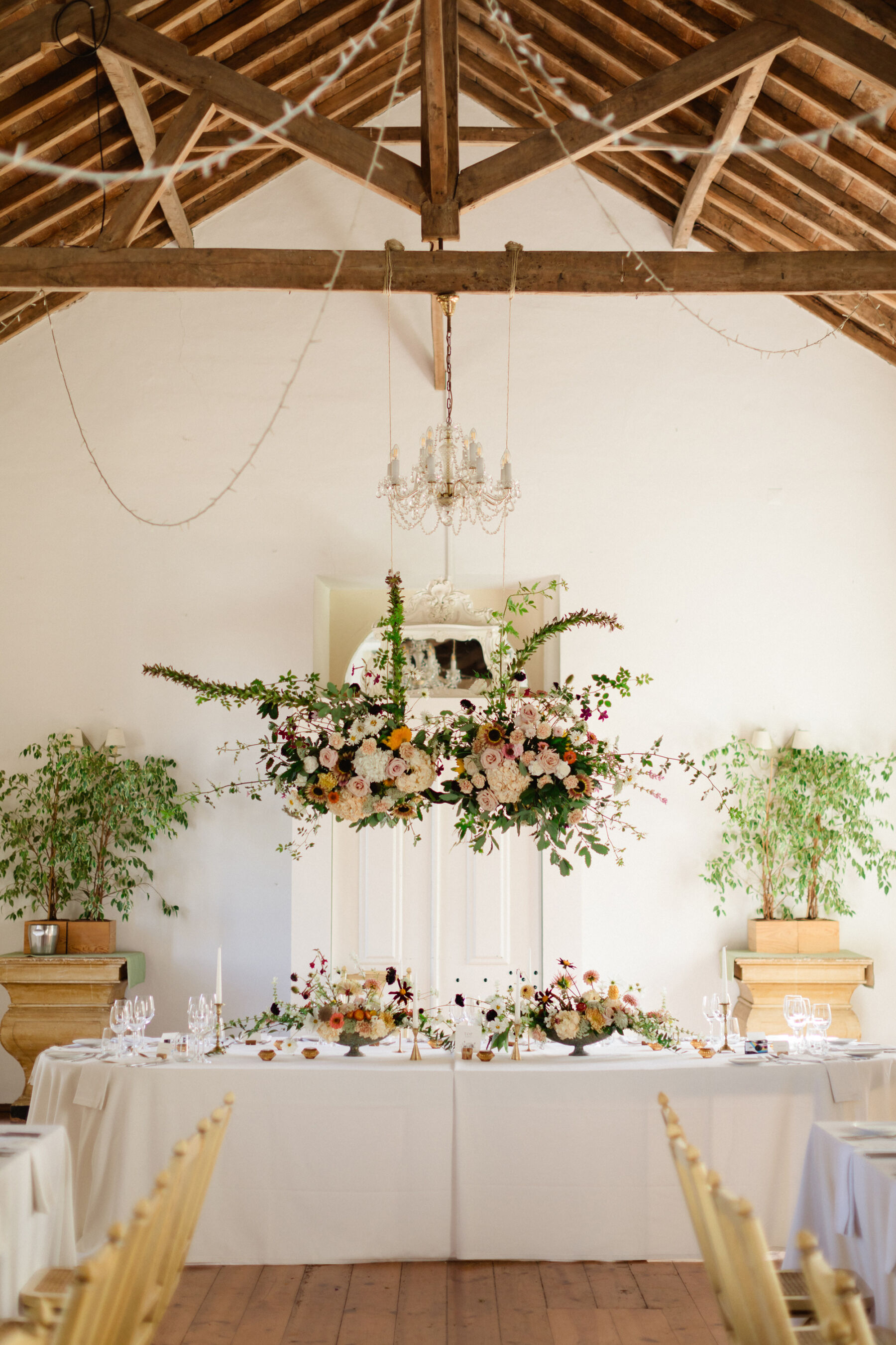 Olivia & Tim's Classy & Elegant Vineyard Wedding in Portugal 39 Flowers like a floral cloud suspended above a top table at a wedding reception.
