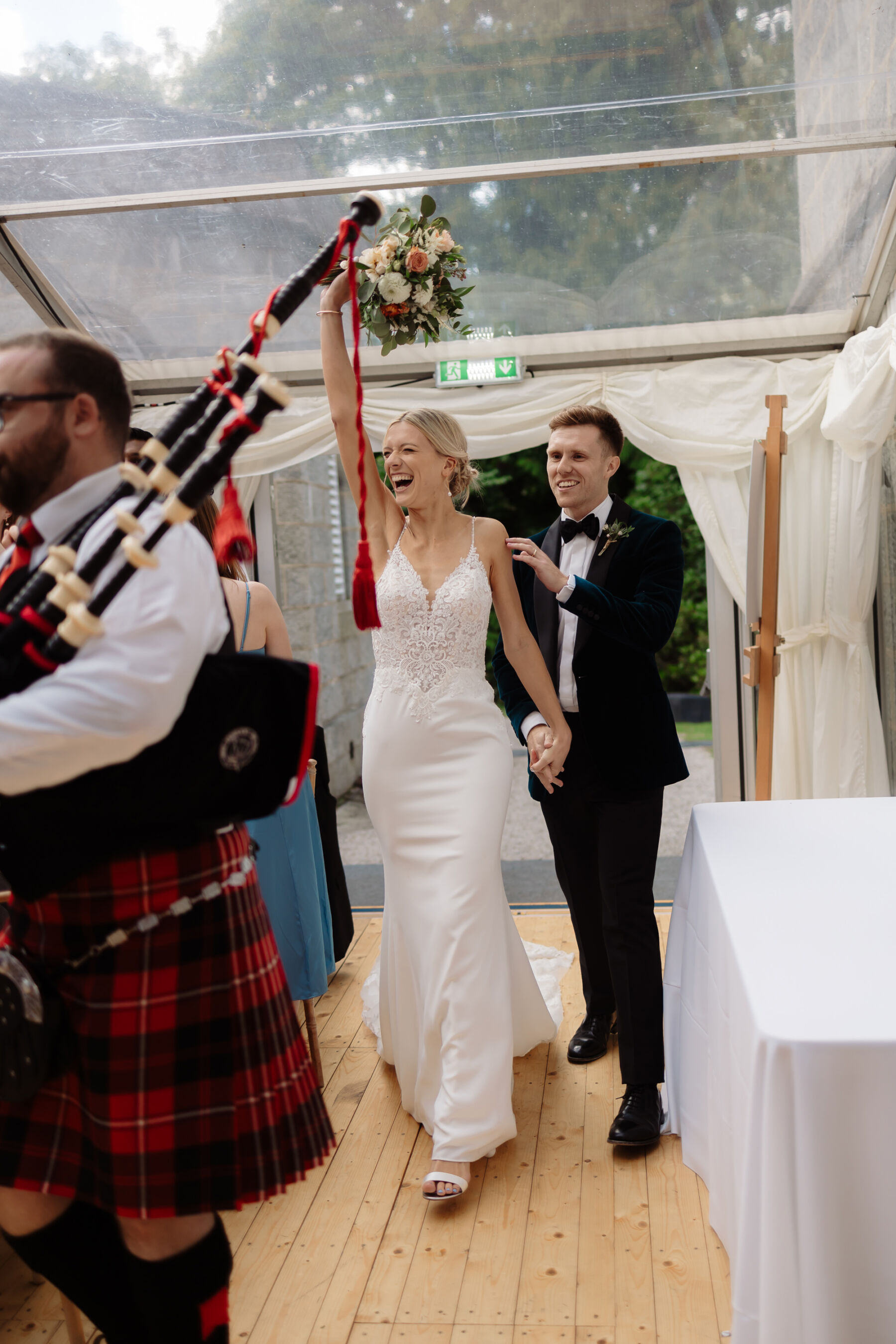 Emily in Rosa Clara for her Romantic & Elegant July Wedding at Cluny Castle 34 Bride and groom being heralded by a bag piper as they arrive at their marquee reception at Cluny Castle.