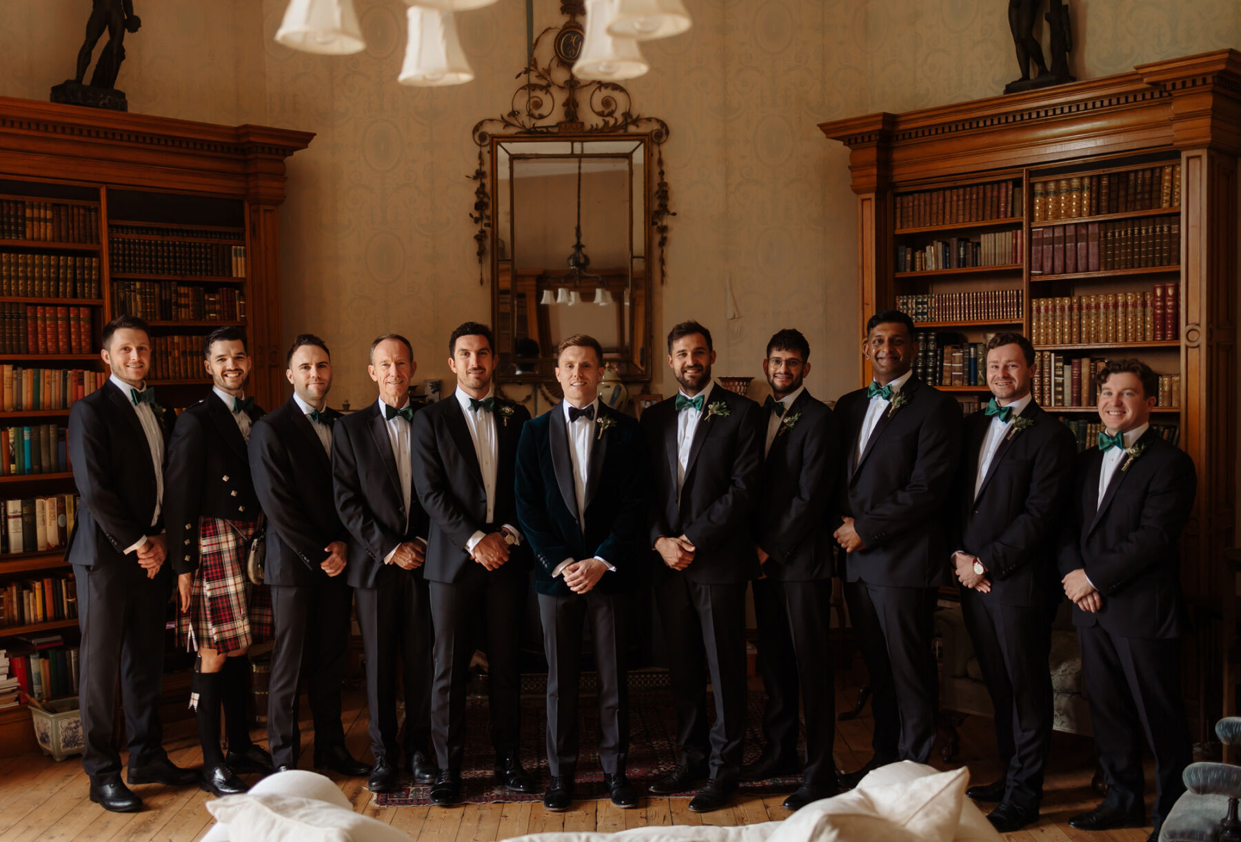 Emily in Rosa Clara for her Romantic & Elegant July Wedding at Cluny Castle 16 Groom and his groomsmen in the library at Cluny Castle in Aberdeenshire. They all wear dark blue tuxedos and bottle green bow ties.