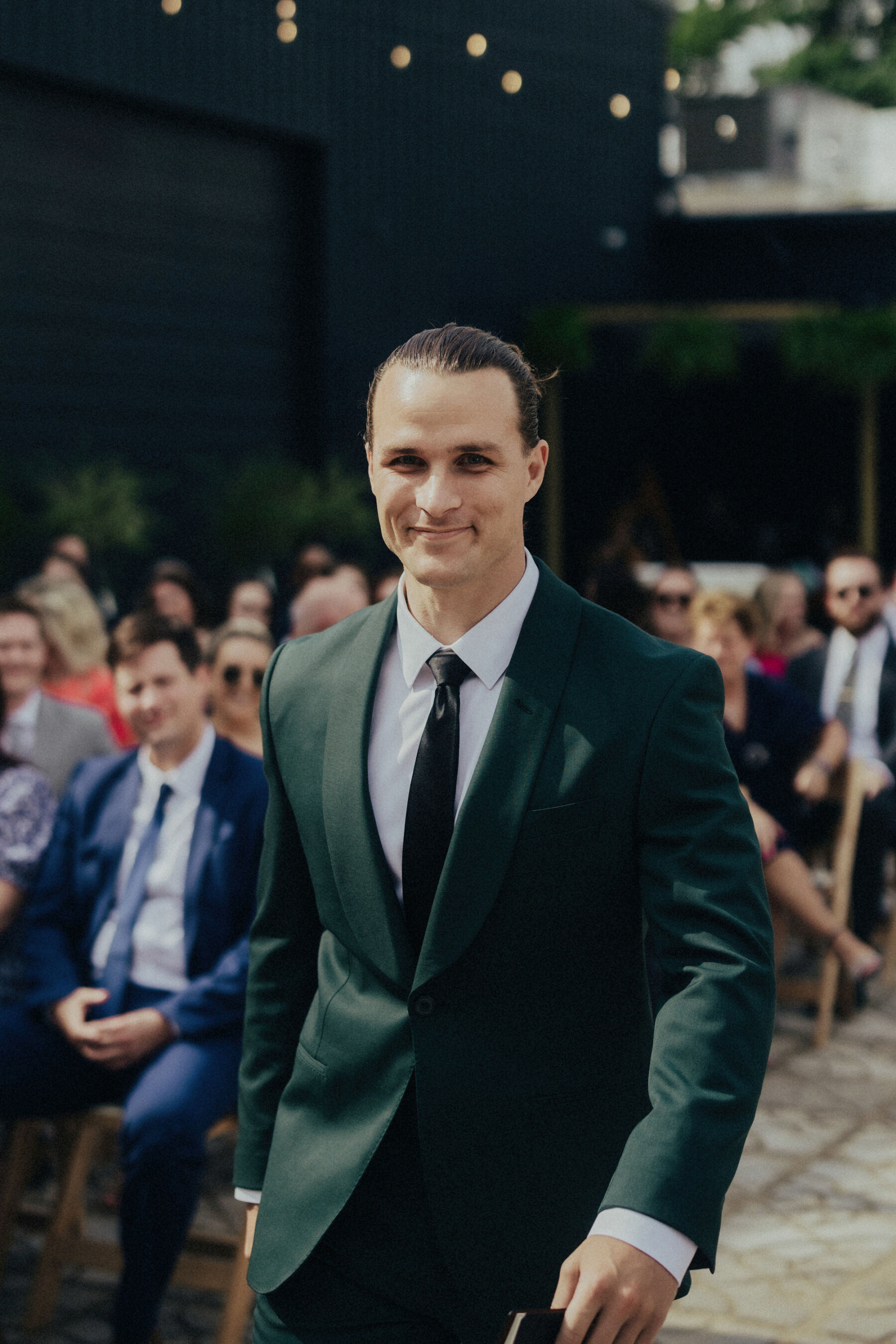 Groom in a dark green suit and black tie.