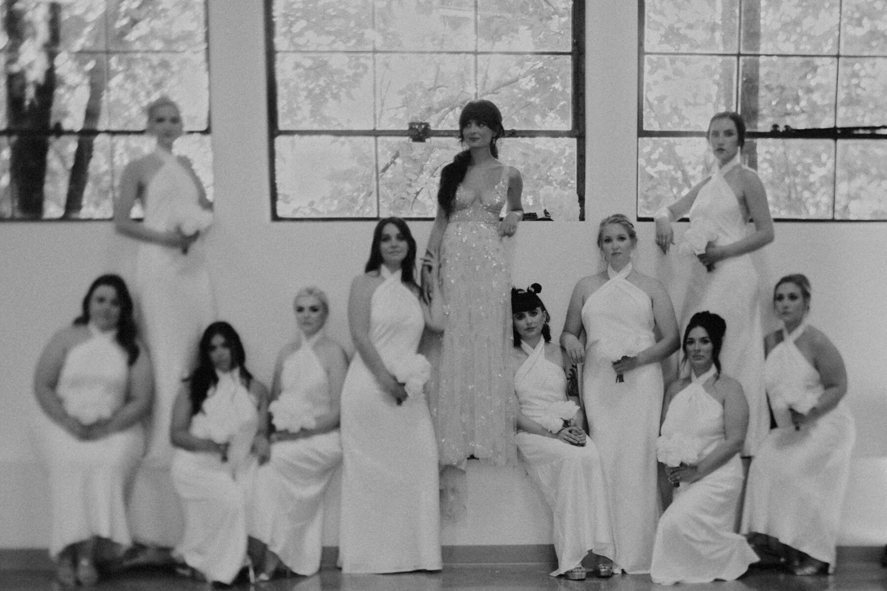 Solange Knowles inspired wedding photograph of bride elevated on a bench platform, surrounded by her bridesmaids in white halterneck dresses. They all look super cool.