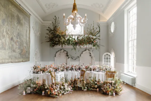 A flower heavy wedding setup on round tables, using premium woven off-white tablecloths