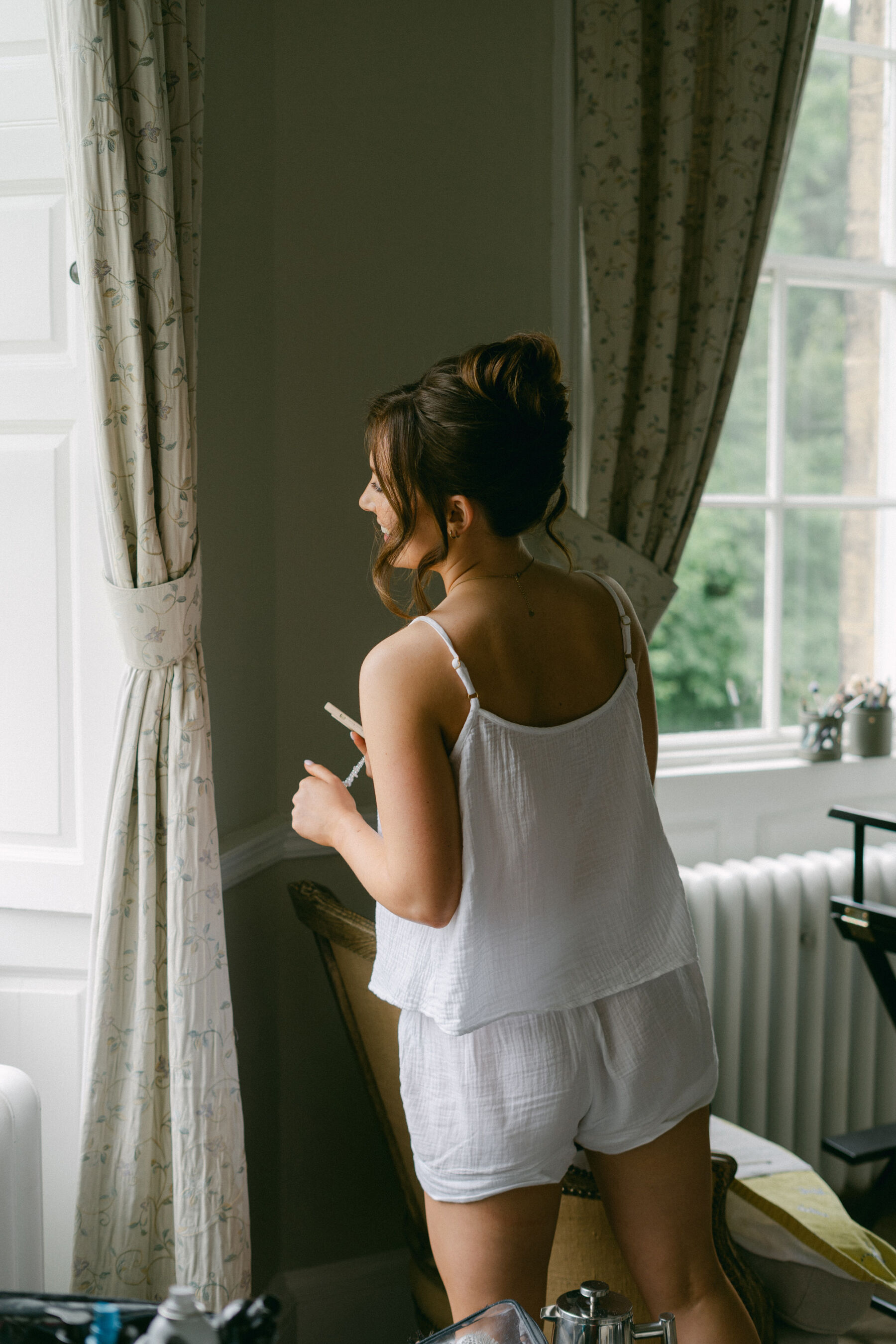 Bride in cotton short pyjamas with an elegant up do and tousles.