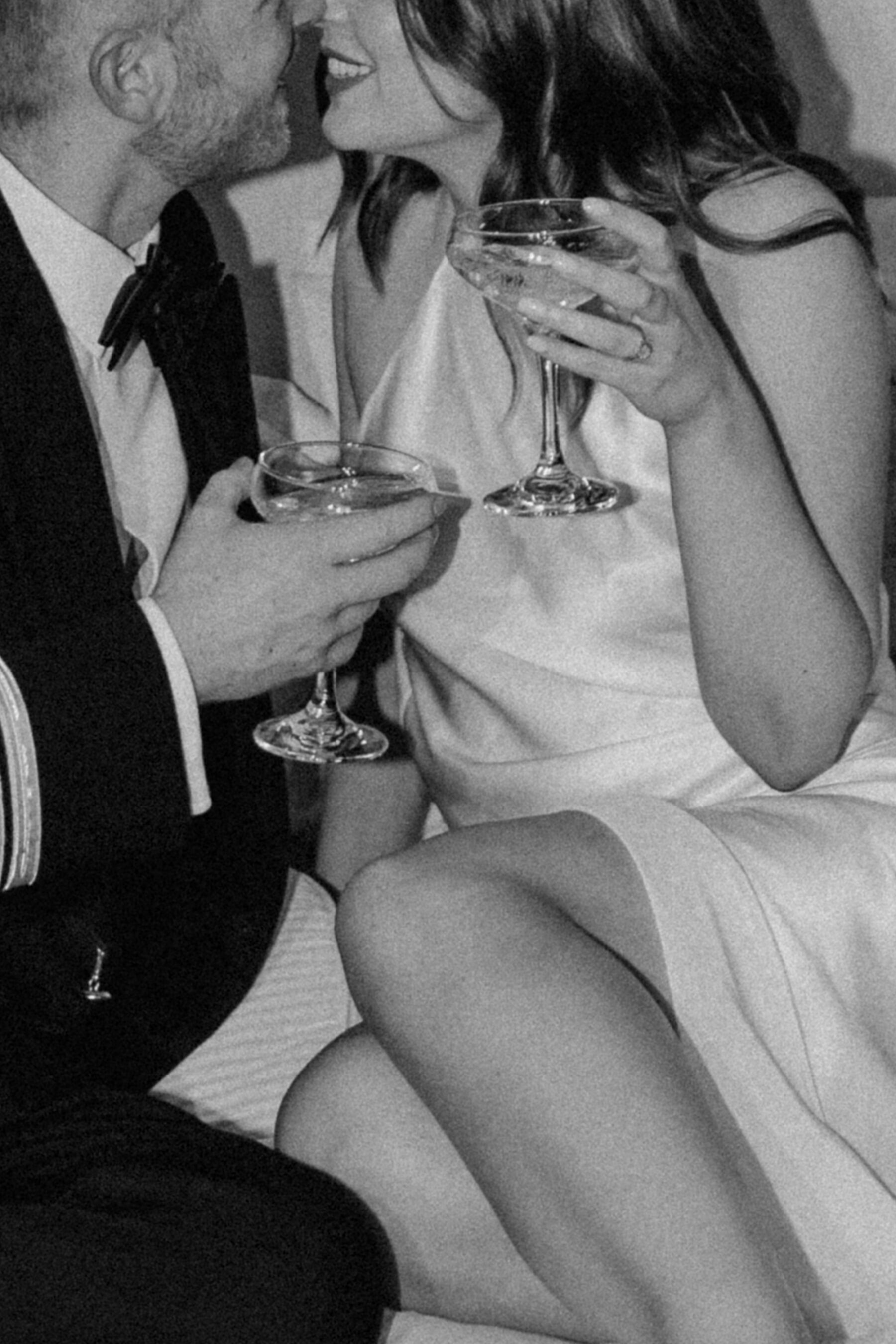 Romantic image of bride and groom kissing and cuddling whilst sipping champagne. 