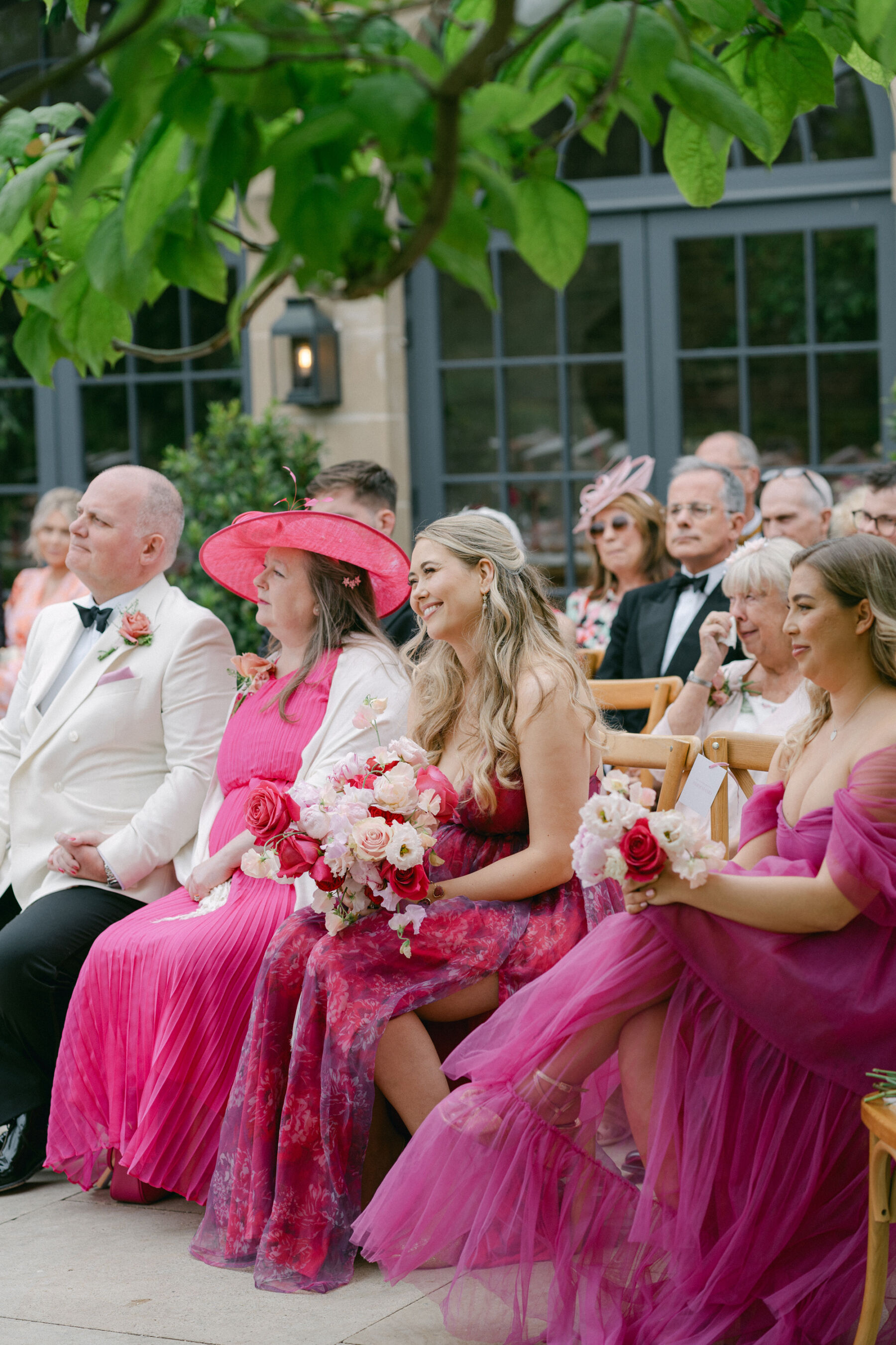 Bridesmaids in pink seated during a wedding ceremony at Middleton Lodge.