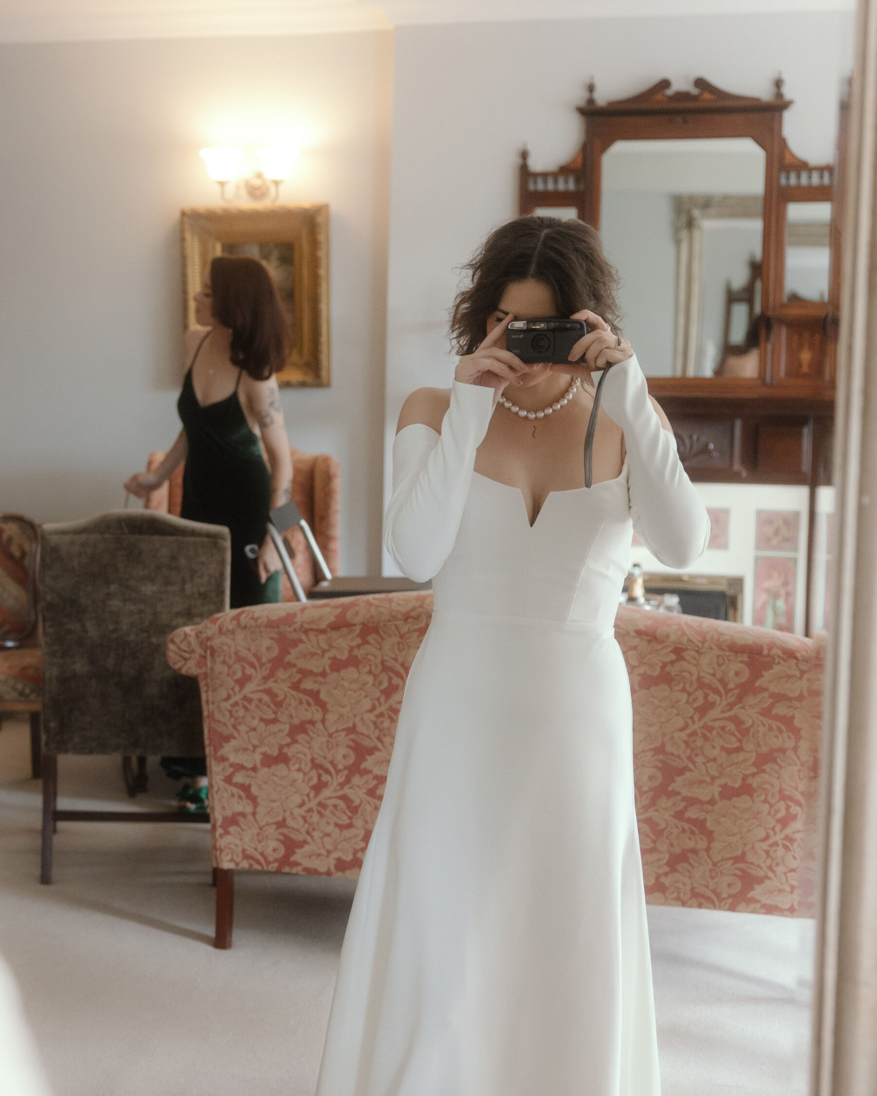 A Mystical, Medieval Inspired Wedding at Tinakilly Country House, Featuring Sarah Seven & Kamperett 21 Bride taking a photograph of herself in the mirror. She wears a Sarah Seven dress and pearl chocker necklace.