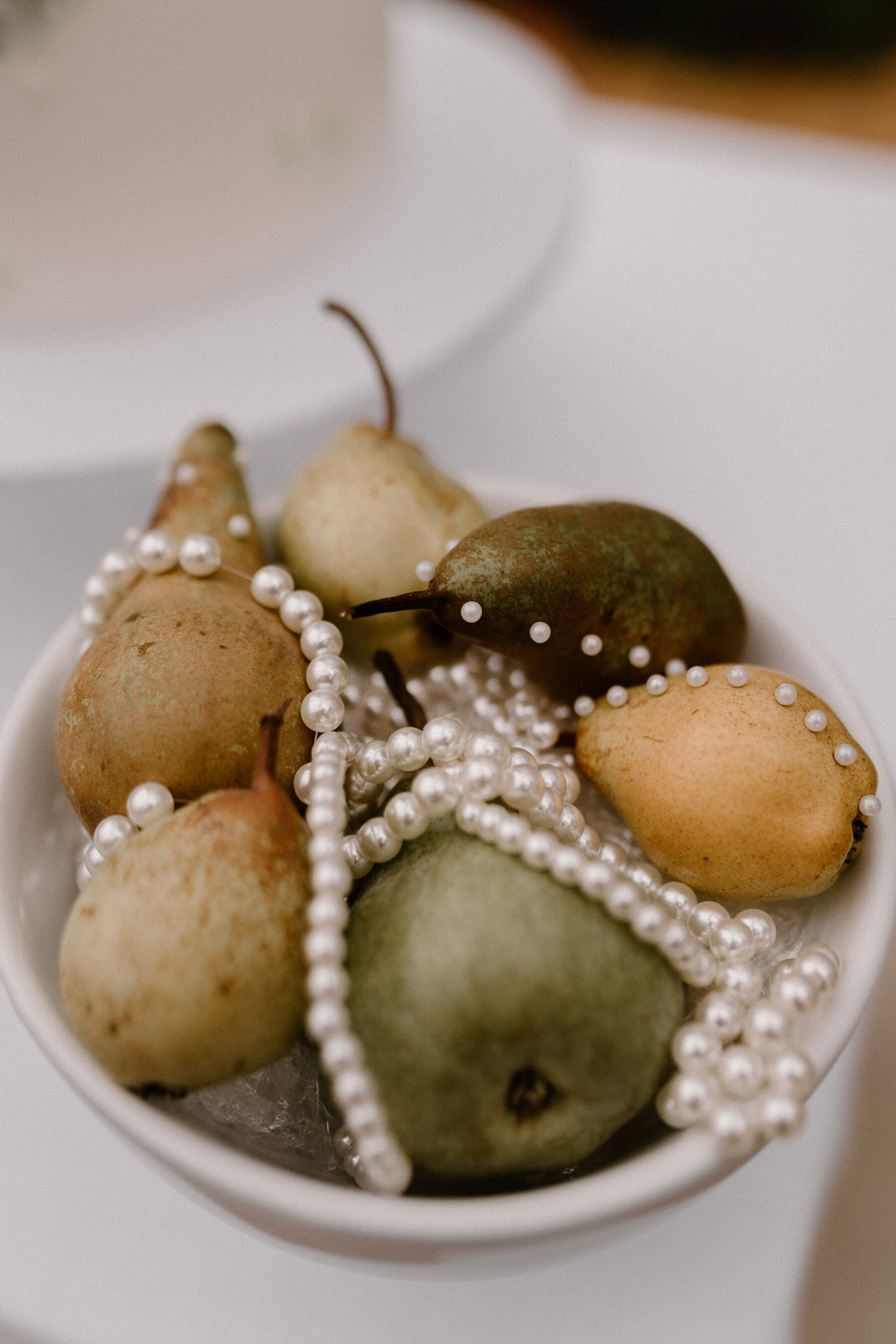 A bowl of pears with pearls strung over them - modern wedding table decor.