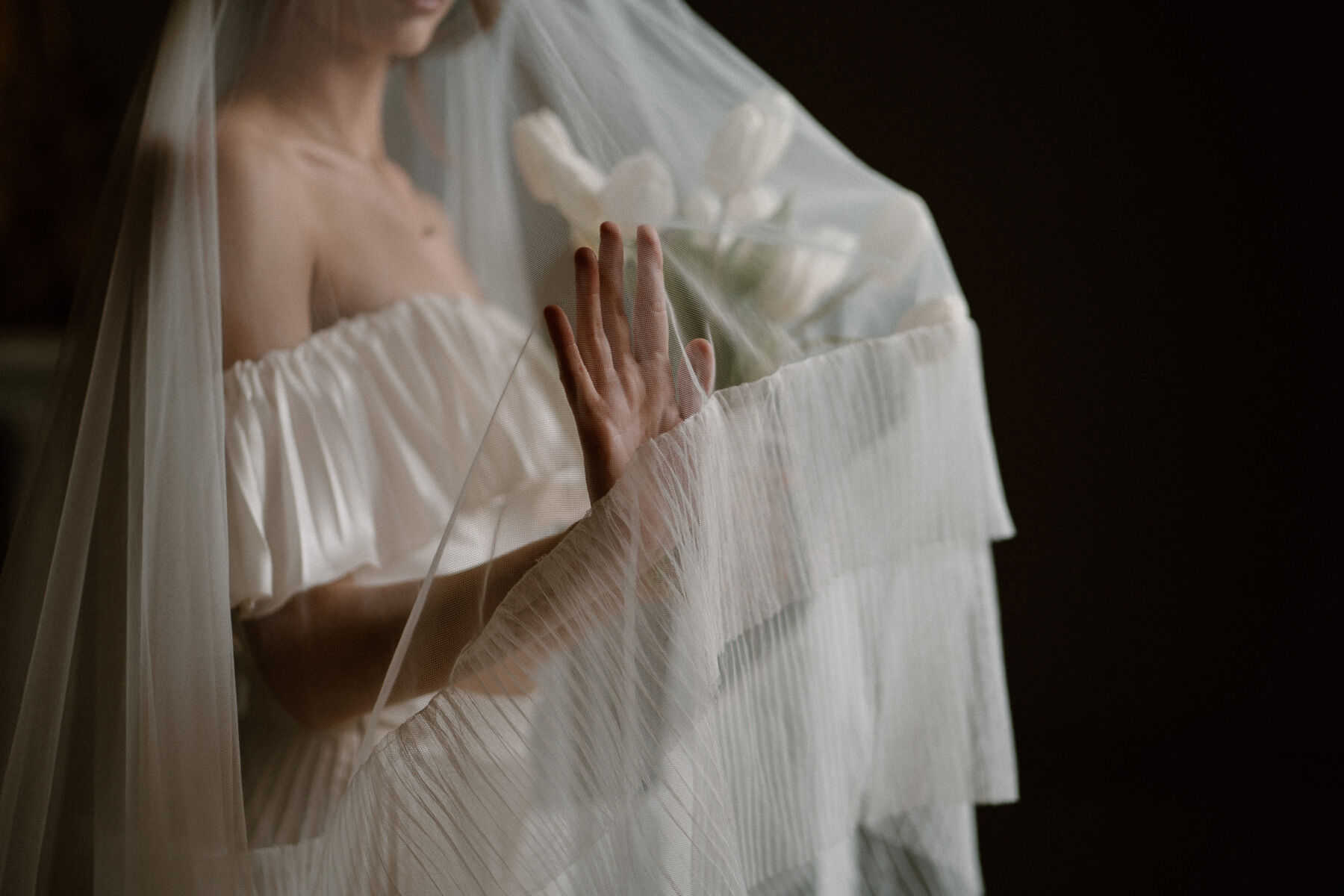 Headloss shot of bride - her hand visible through a delicate veil with a pleated trim. Veil by Rebecca Anne Designs.