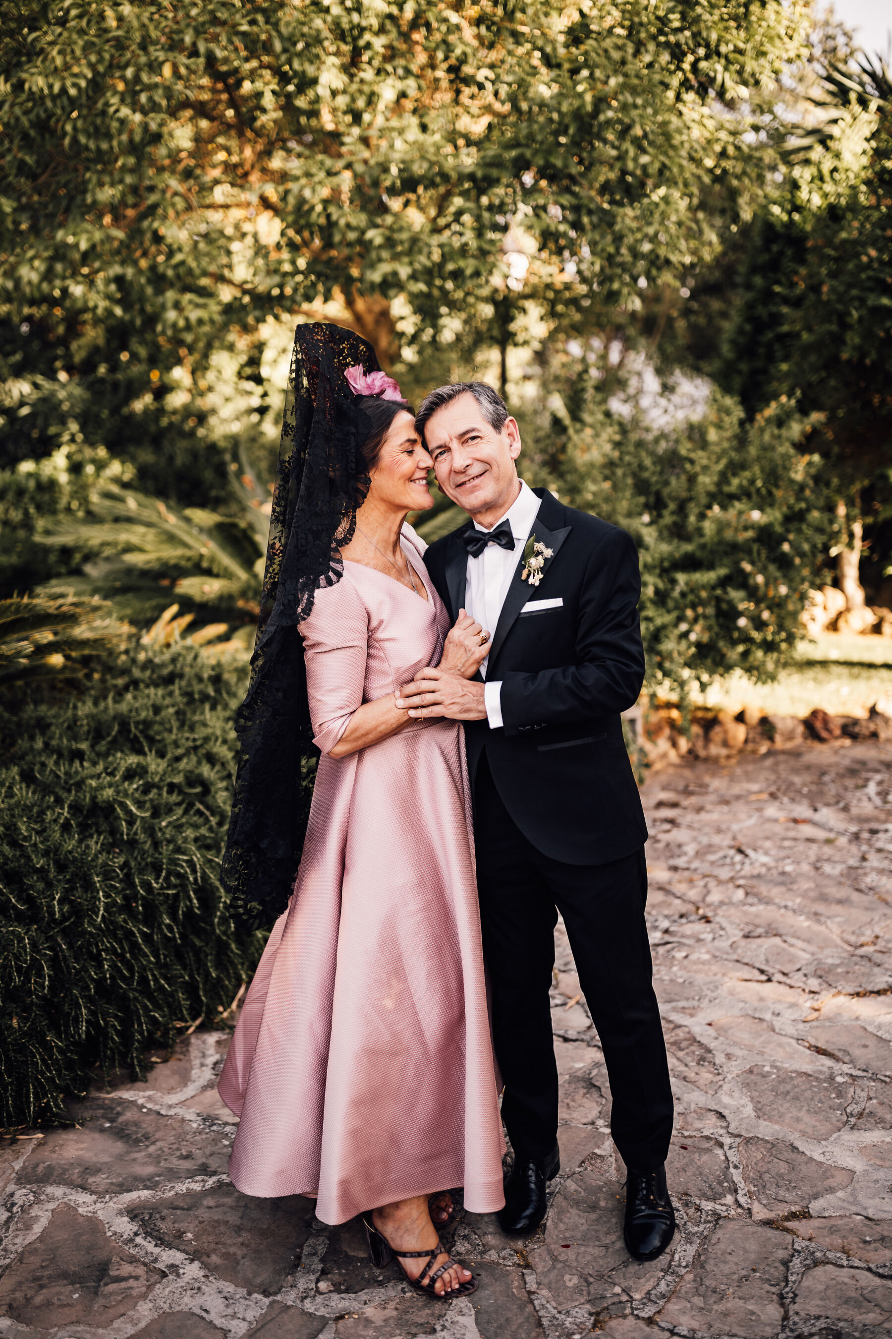 Alexandra Wore Phillipa Lepley For Her Romantic Destination Wedding in Spain 19 Mother of the groom in a traditional black mantilla veil and pink silk dress. She is being embraced by the father of the groom.