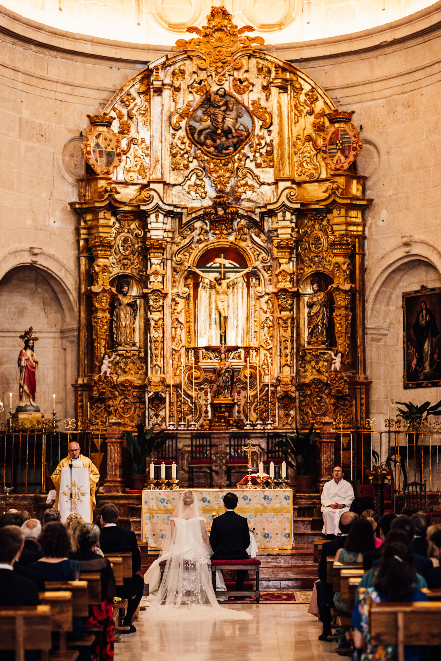 Alexandra Wore Phillipa Lepley For Her Romantic Destination Wedding in Spain 24 Bride and groom seated at the elaborate gold altar in a church in Spain during their destination wedding.