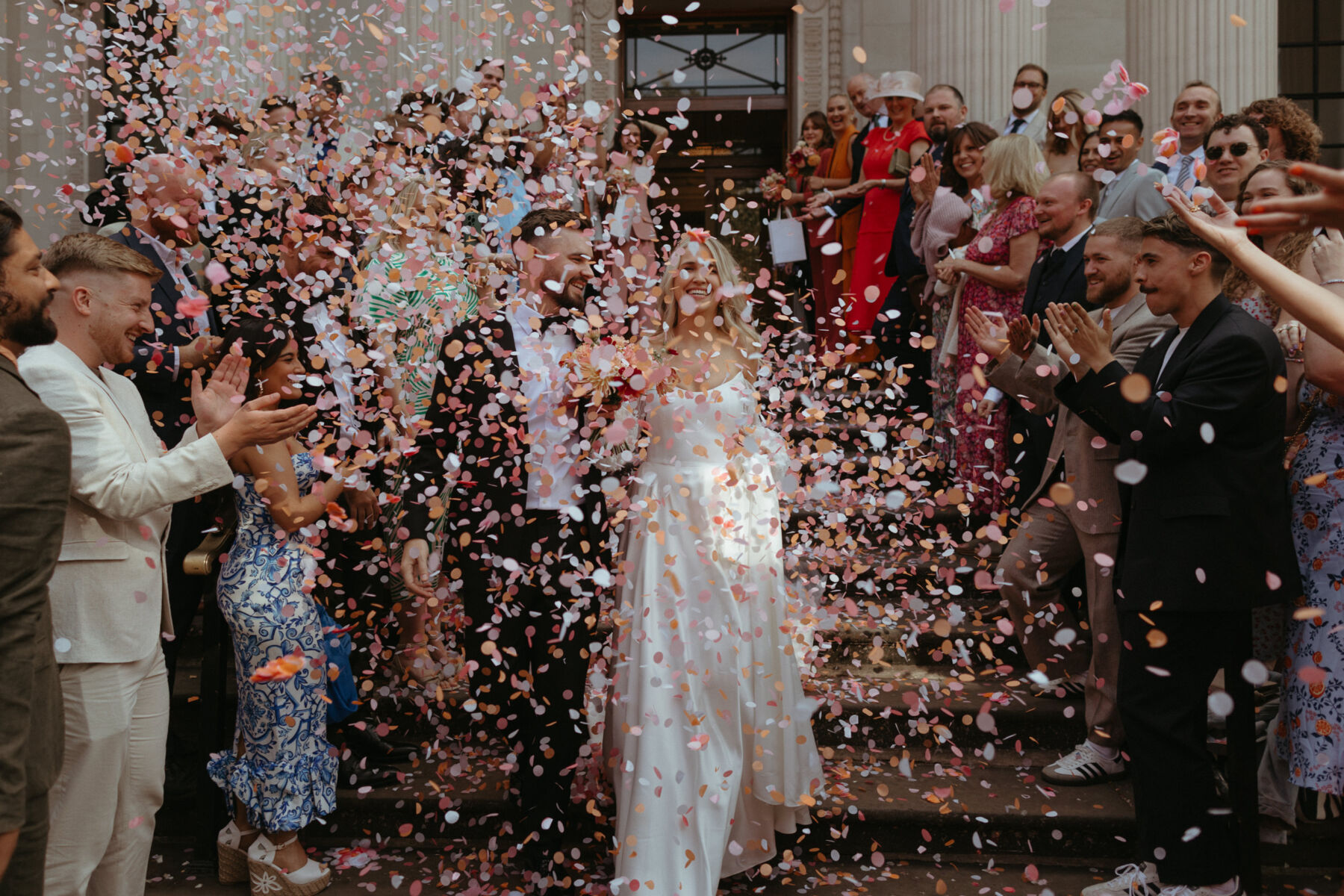 Georgia in Truvelle for her Modern London Wedding at The Depot in Islington 12 Confetti shot of a couple having just married at Old Marylebone Town Hall in London. They are being showered in pastel colour paper circles of confetti.