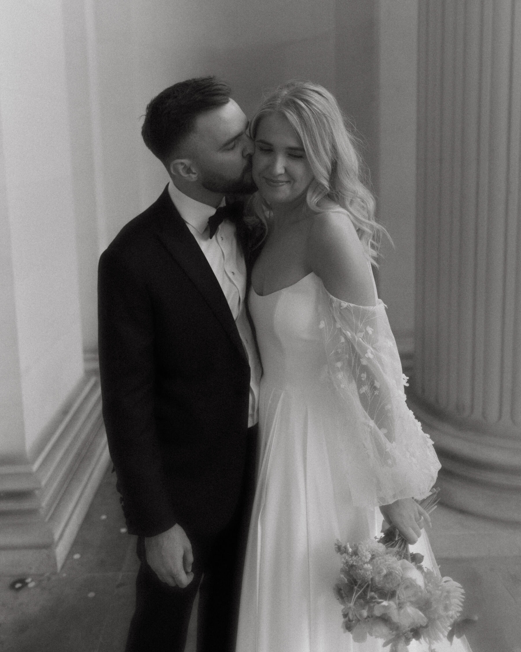 Georgia in Truvelle for her Modern London Wedding at The Depot in Islington 15 Black and white portrait of couple leaning into one another and kissing outside Old Marylebone Town Hall in London.