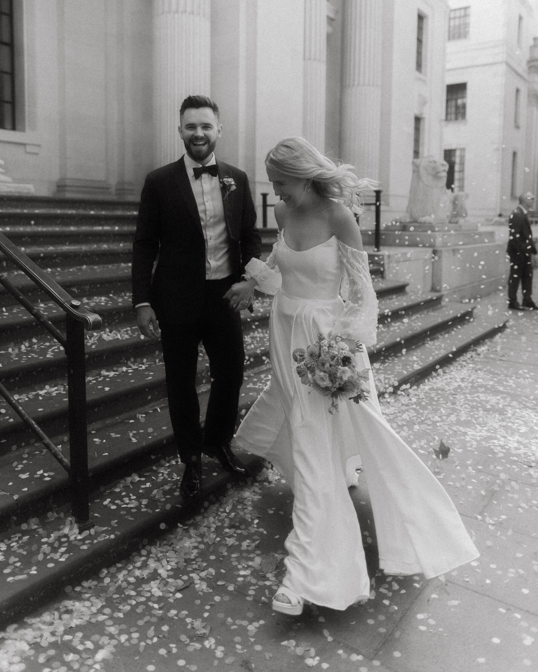 Georgia in Truvelle for her Modern London Wedding at The Depot in Islington 14 Black and white portrait of couple walking down the steps at Old Marylebone Town Hall in London.