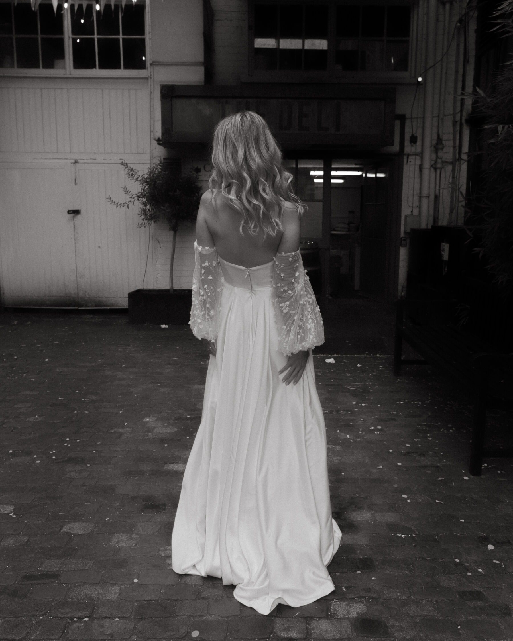 Georgia in Truvelle for her Modern London Wedding at The Depot in Islington 16 Black and white photograph of the back of a bride in a strapless Truvelle wedding dress with detachable sleeves.