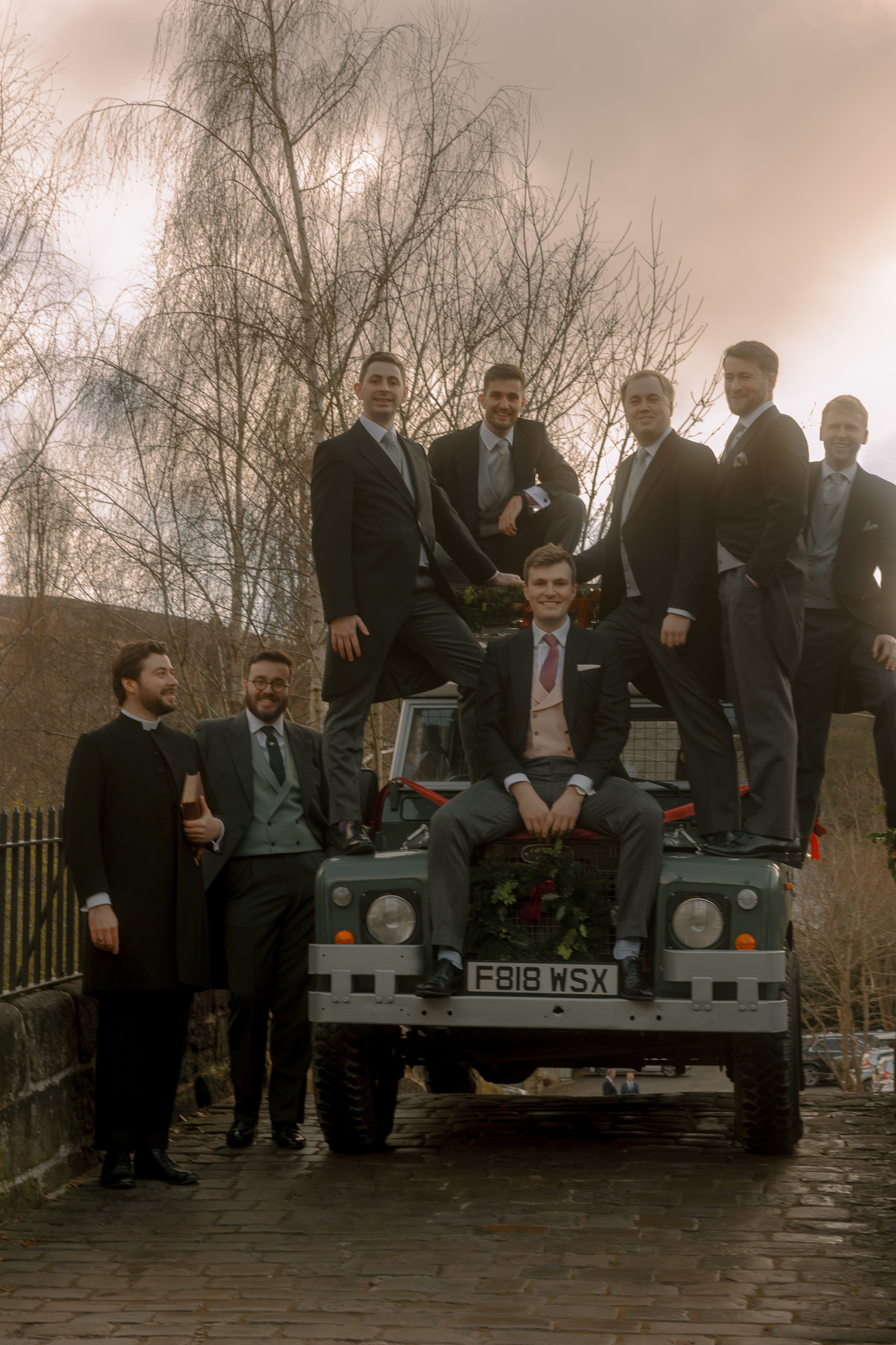 A Movie & Literary Inspired Romantic Christmas Wedding 17 Groom and his groomsmen on a Christmas wedding day sat and stood by a Landrover.