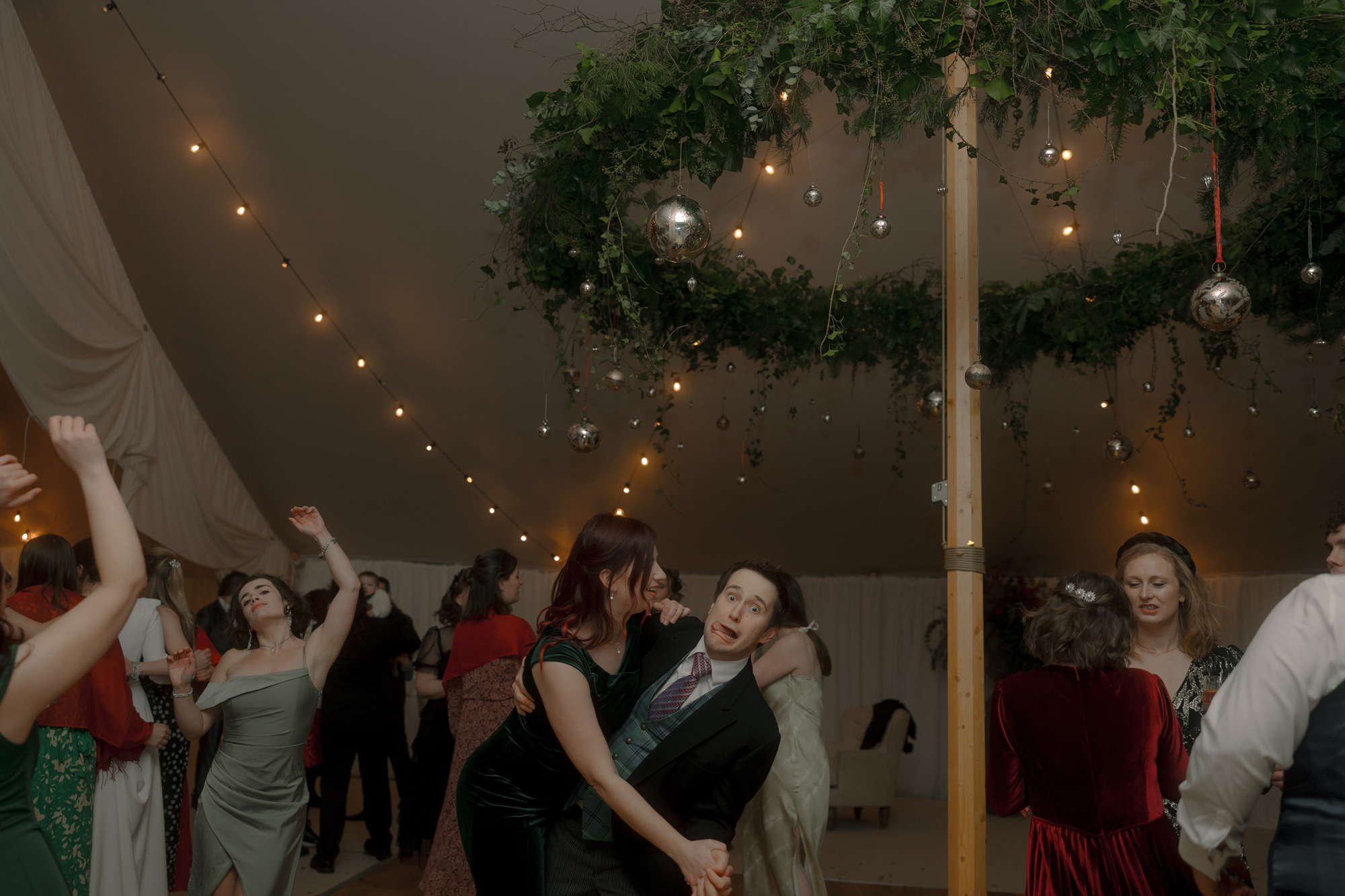 A Movie & Literary Inspired Romantic Christmas Wedding 95 Wedding guests dancing on a wedding marquee dance floor at a Christmas wedding, surrounded by festoon lights.