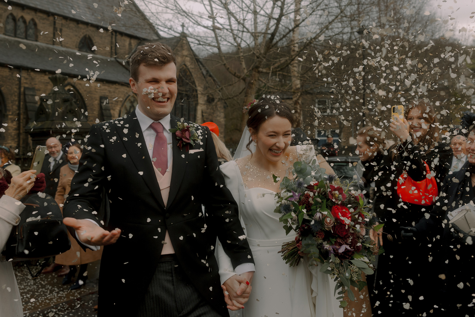 Christmas wedding with bride wearing a Suzanne Neville wedding dress leaving church with her groom being showered in confetti