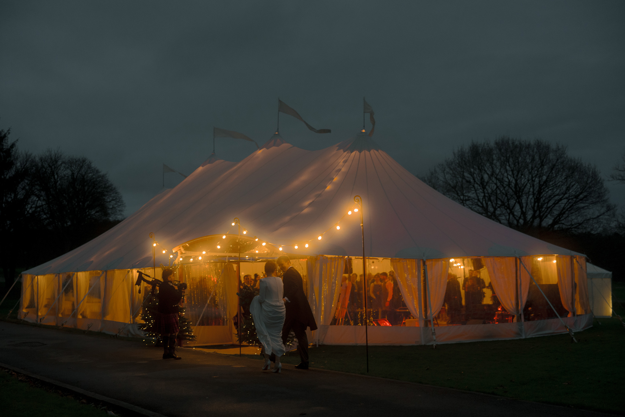 A Movie & Literary Inspired Romantic Christmas Wedding 59 Bride and groom approaching their Christmas wedding marquee decorated with festoon lights.