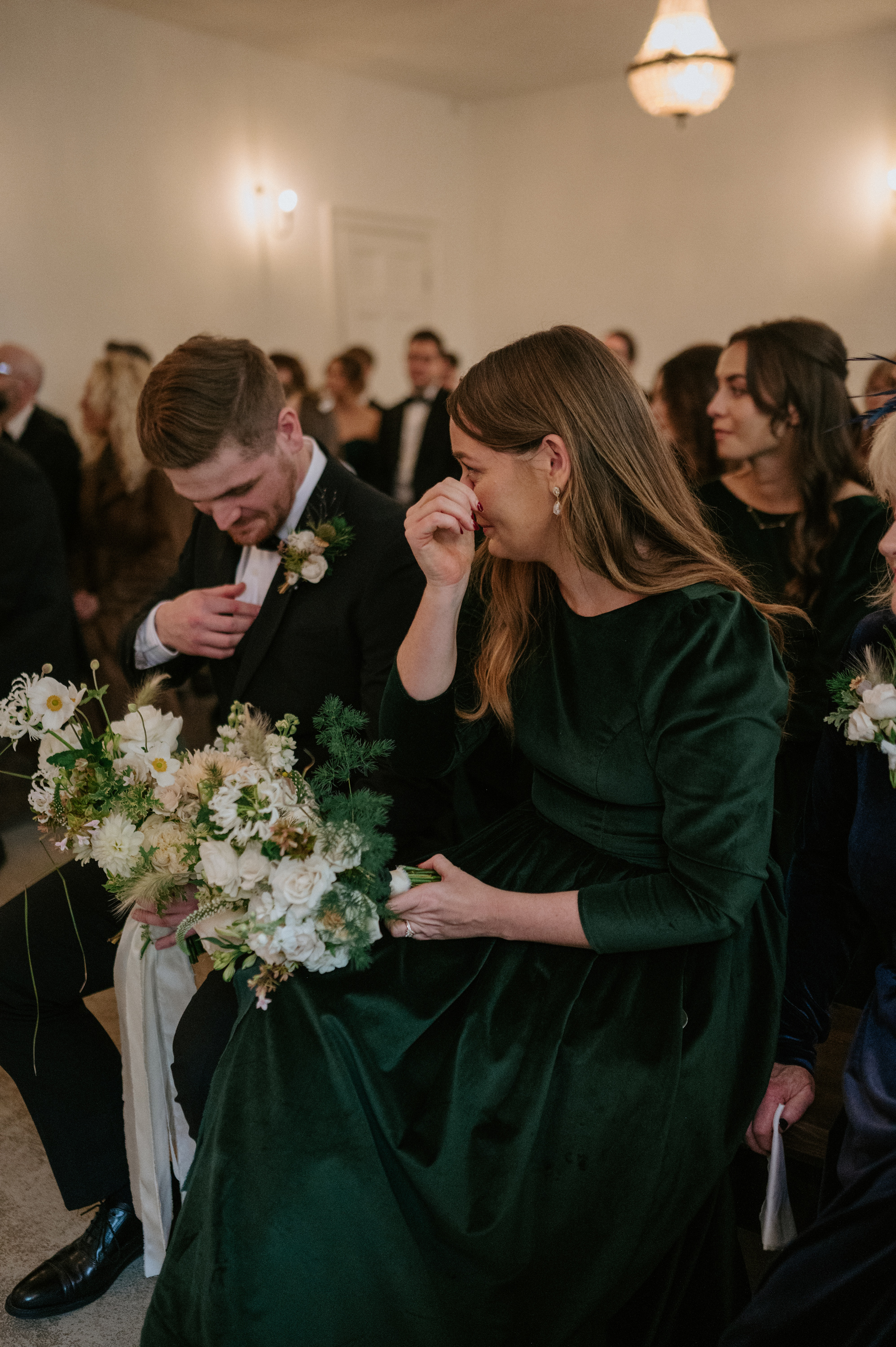 Bridesmaids wearing dark green velvet dresses and clutching elegant neutral bouquets 