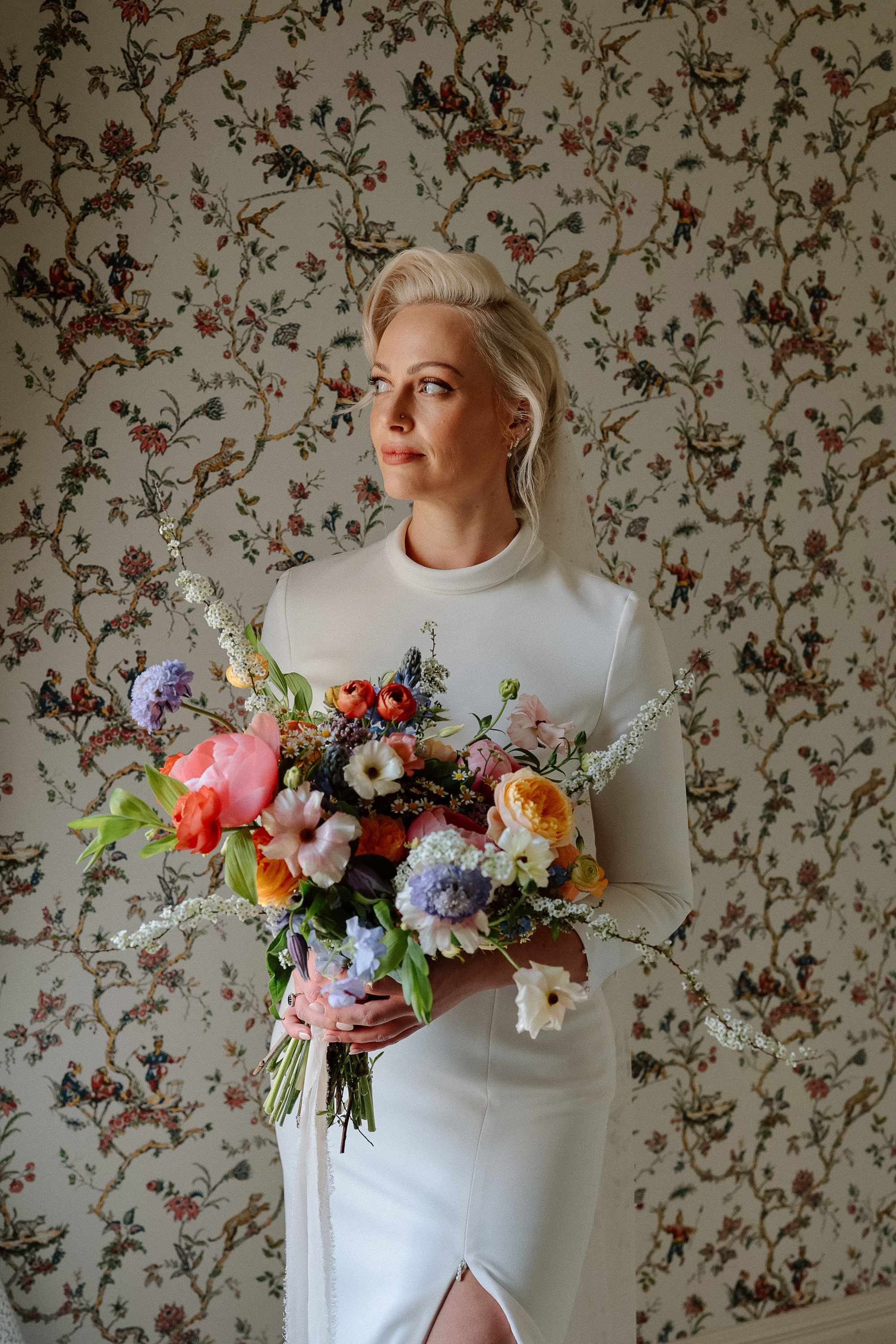 Bon Bride Elegance for a Stylish Healey Barn Wedding in Northumberland 17 Bride with platinum blonde hair carrying a large colourful spring wedding bouquet and wearing a Bon Bride wedding dress.