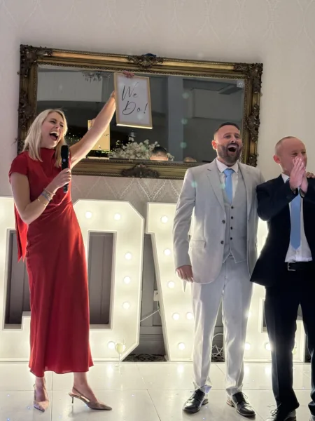 Katie Isles Celebrant holding up a WE DO sign for two grooms