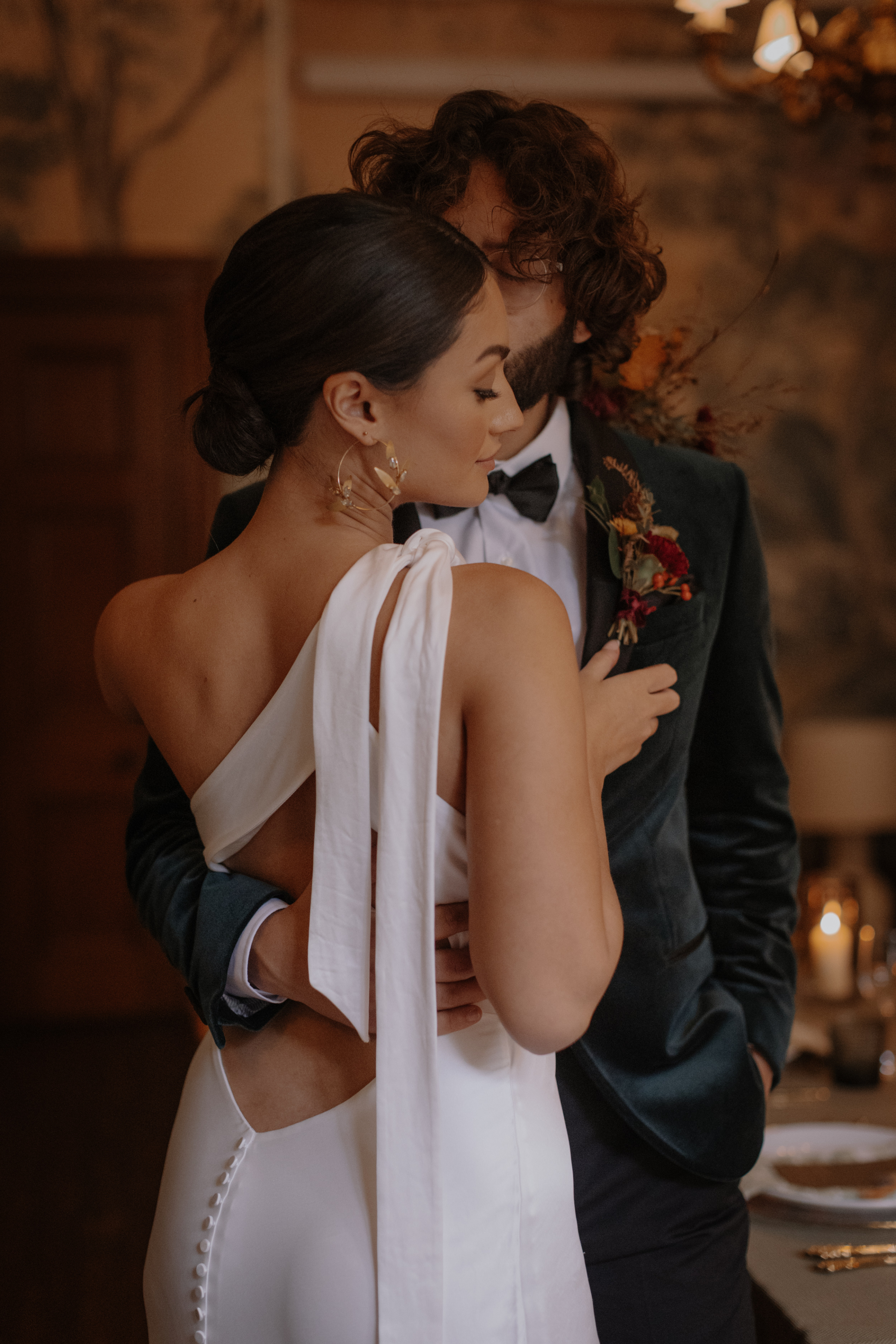 Bride wearing a modern asymmetrical wedding dress with a shoulder strap that hangs down her back.
