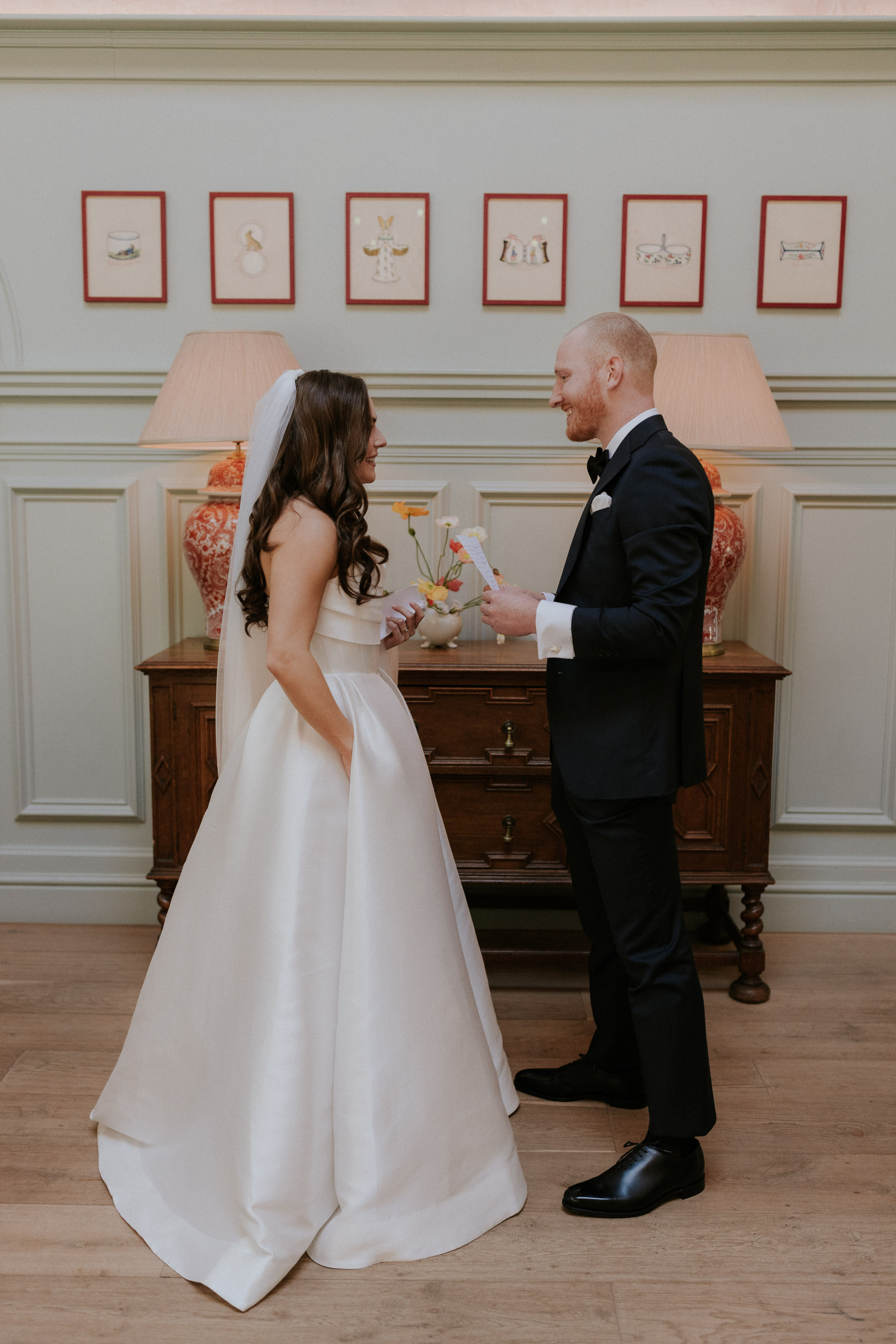 A Romantic Summer Wedding at Kin House in Wiltshire 32 First look. Kin House Wiltshire. Bride wears an Alex Perry gown. The couple stand in a panelled room exchanging vows. Maja Tsolo Photography.