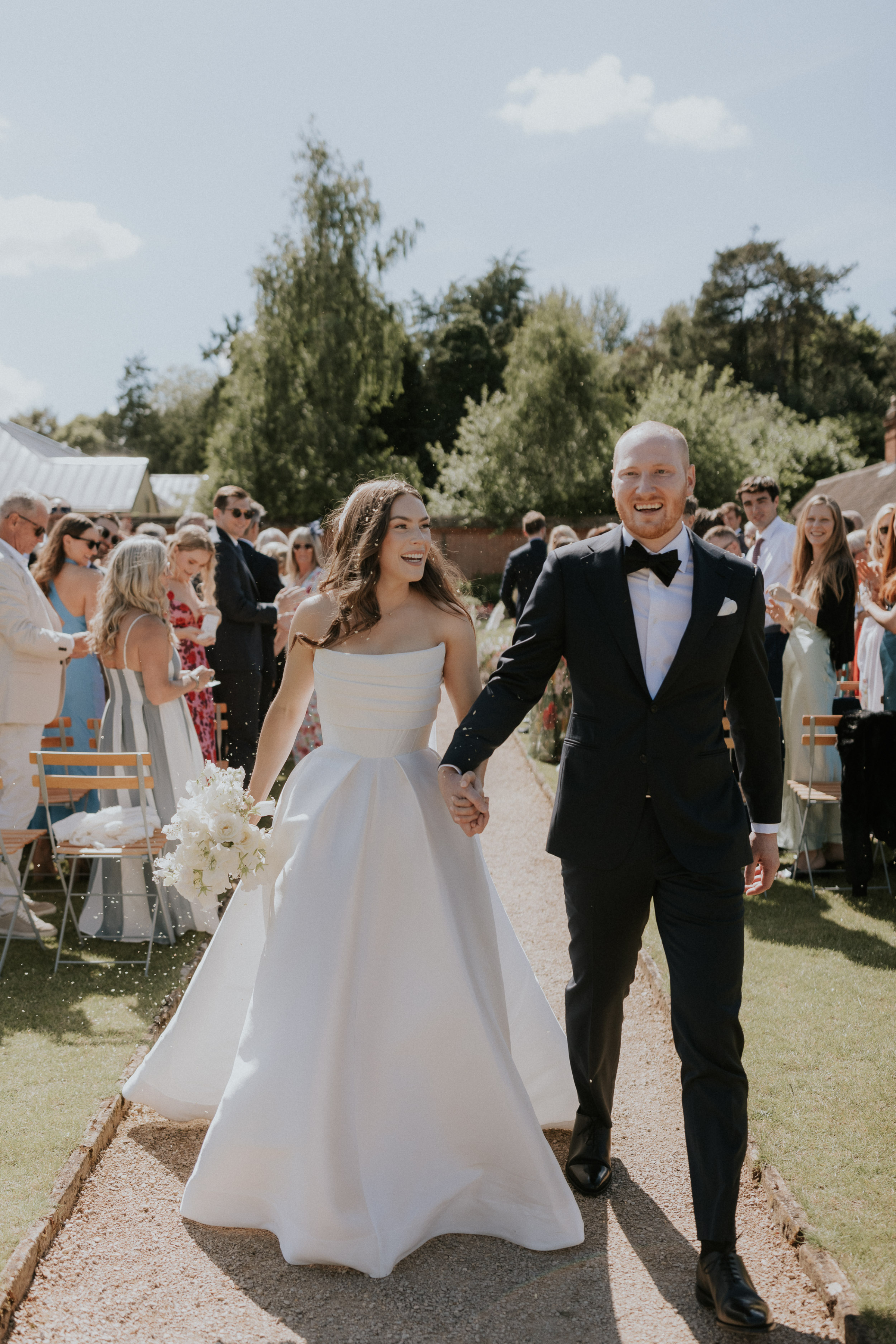 A Romantic Summer Wedding at Kin House in Wiltshire 36 Just married joy! Couple walking back down the aisle for their wedding ceremony at Kin House in Wiltshire. Groom in black tie, bride in an Alex Perry ballgown inspired wedding dress. Maja Tsolo Photography.