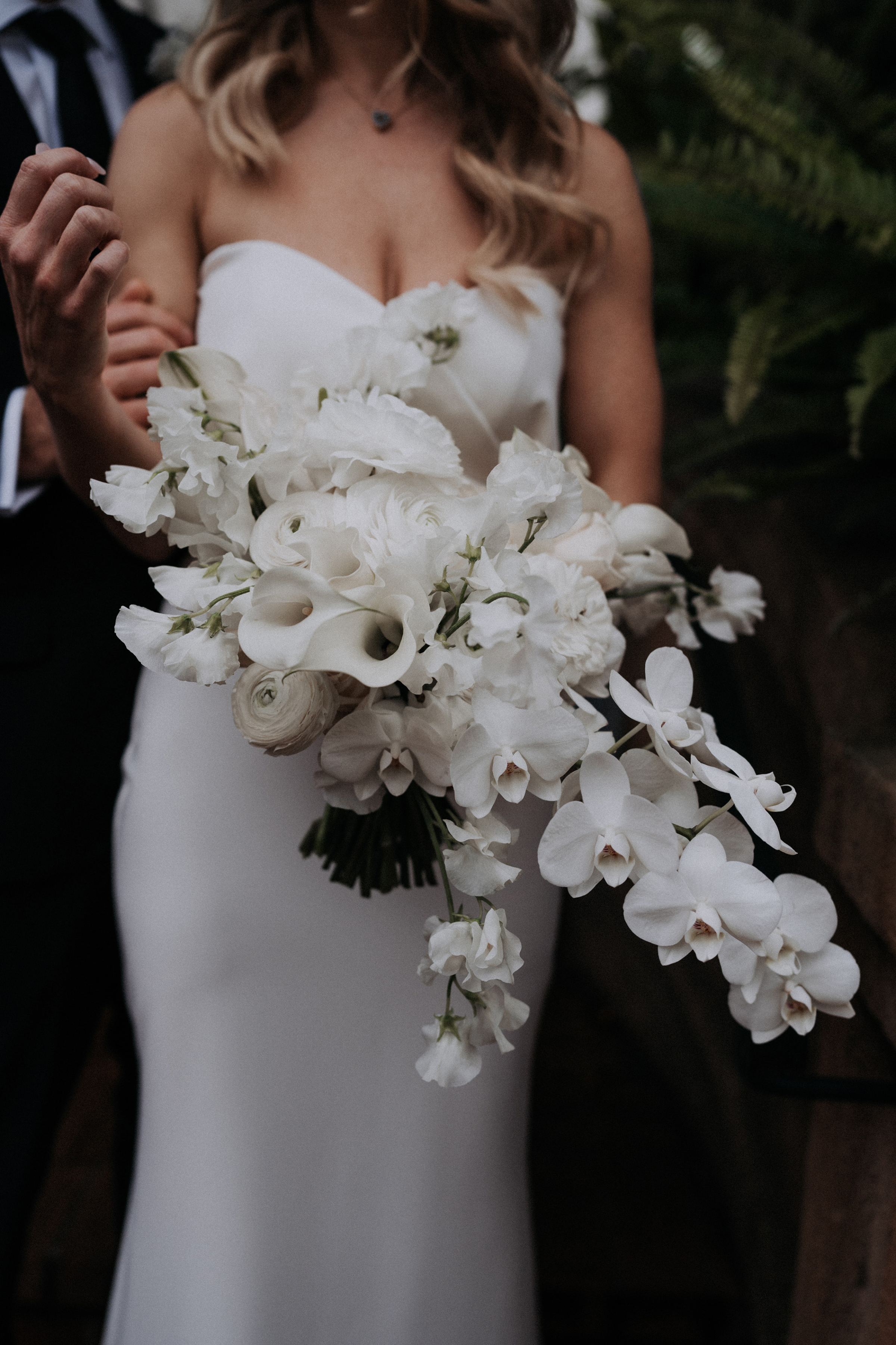 Headless shot of a bride wearing a Made With Love Bridal gown and carries a large, white modern bouquet.