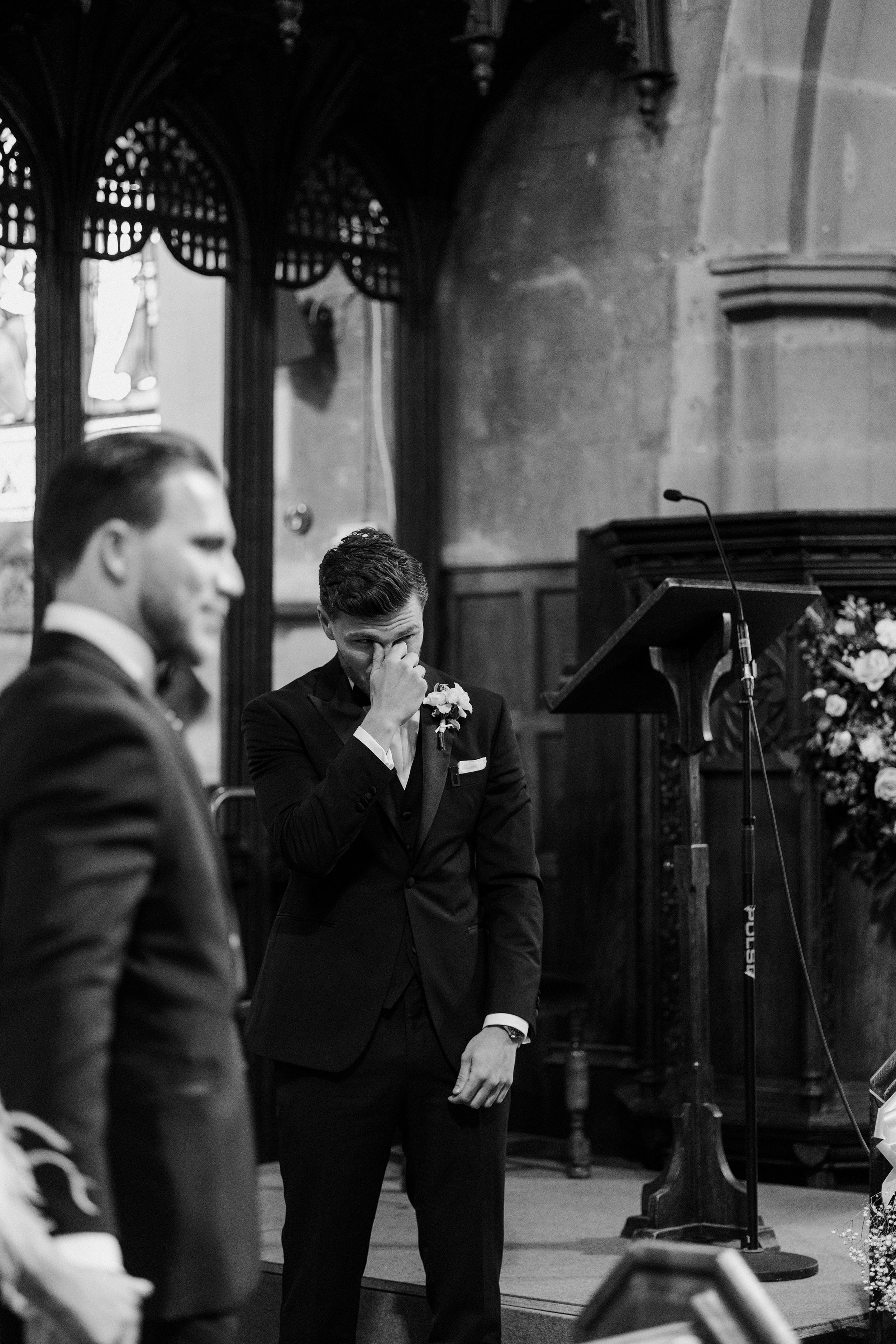 Groom wiping away a tear as he awaits his bride walking down the aisle.