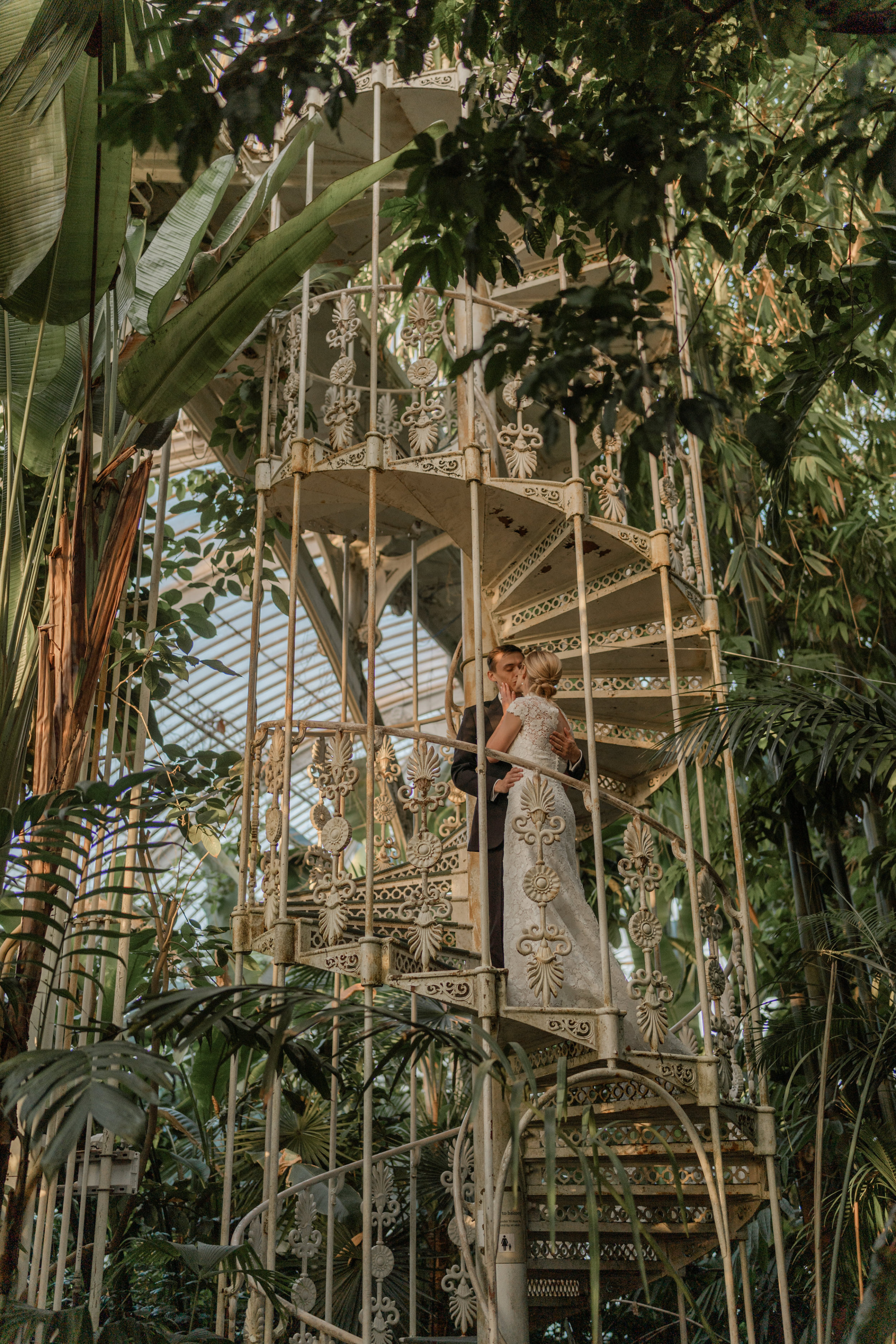 Bride and groom standing on a of wrought iron spiral staircase at Kew Gardens.