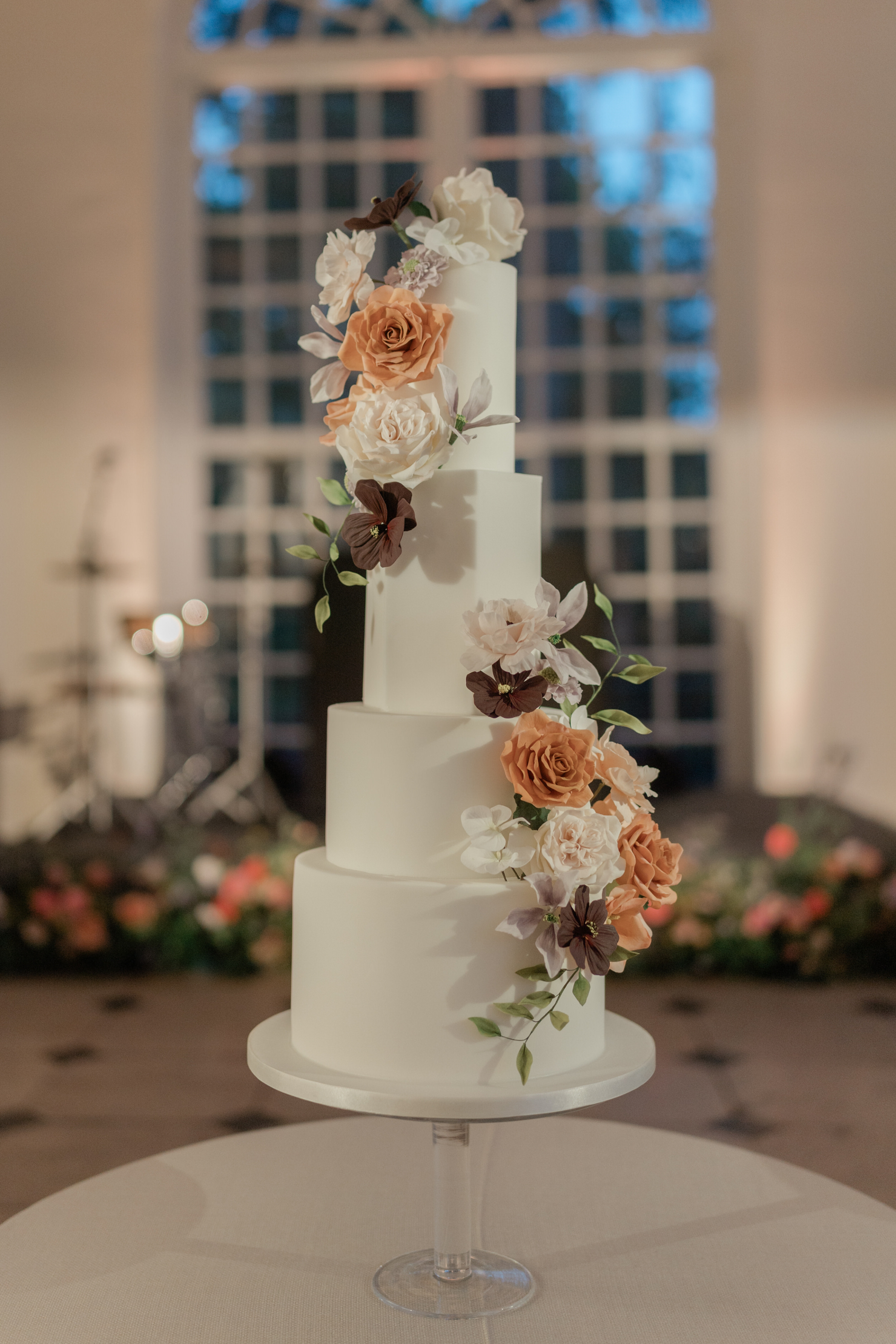 Tall 4 tier wedding cake covered in Autumn flowers. androses.