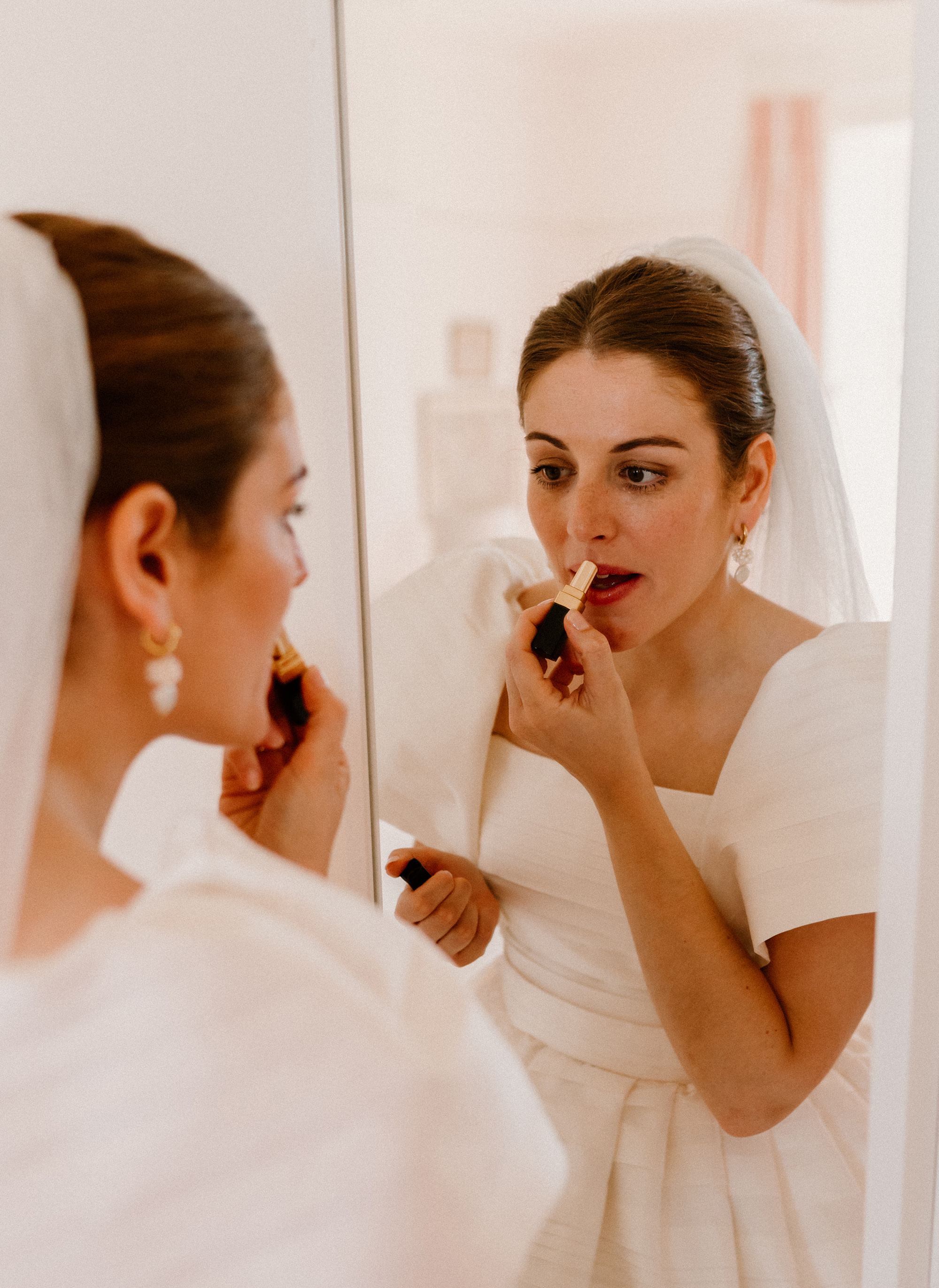 Hannah in Jesus Peiro for her Intimate Brunton House Wedding in Northumberland 20 Bride in a puff sleeved Jesus Peiro wedding dress looking into the wedding dress as she puts her lipstick on.