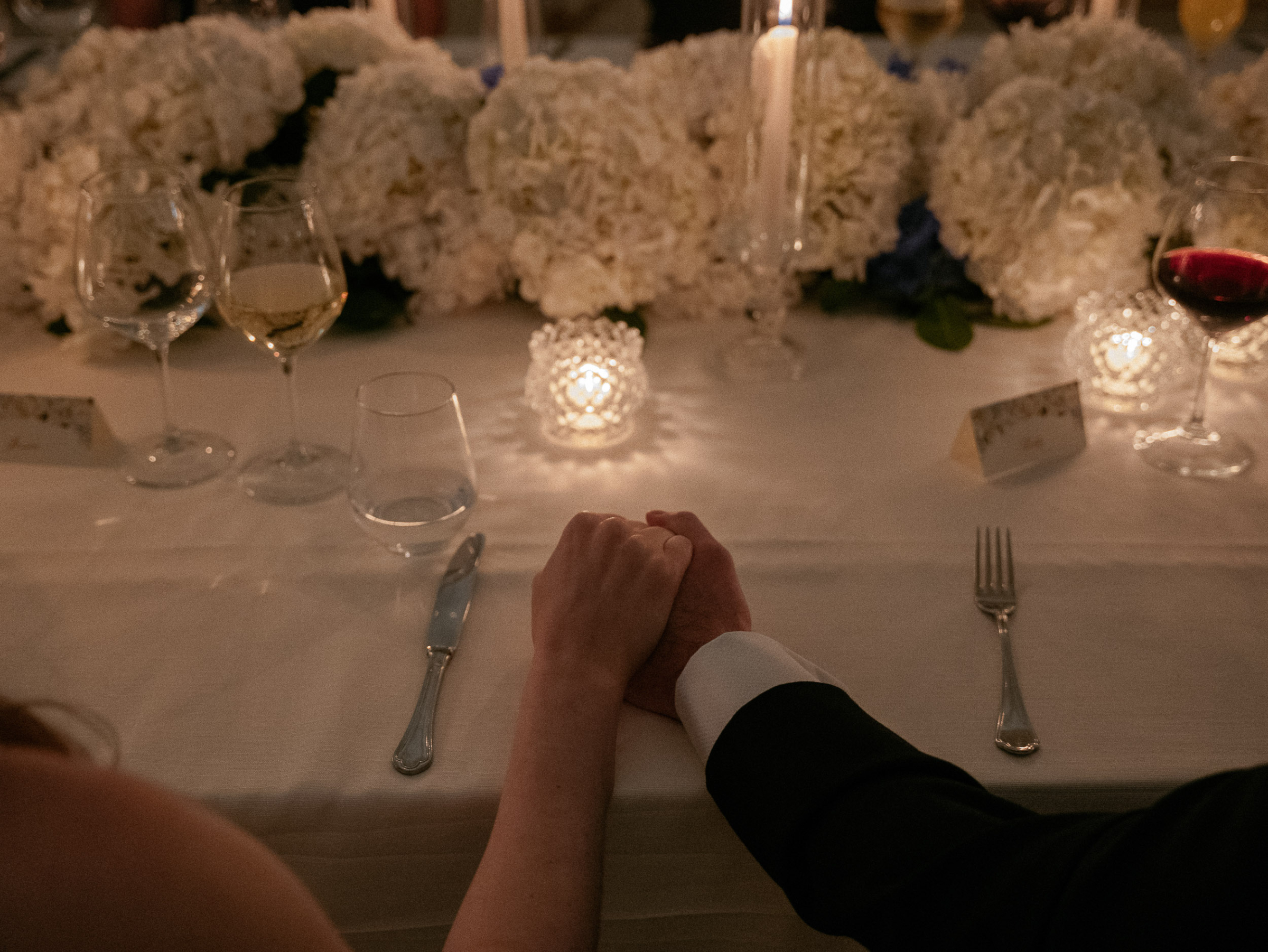 Close up shot of bride and groom holding hands.