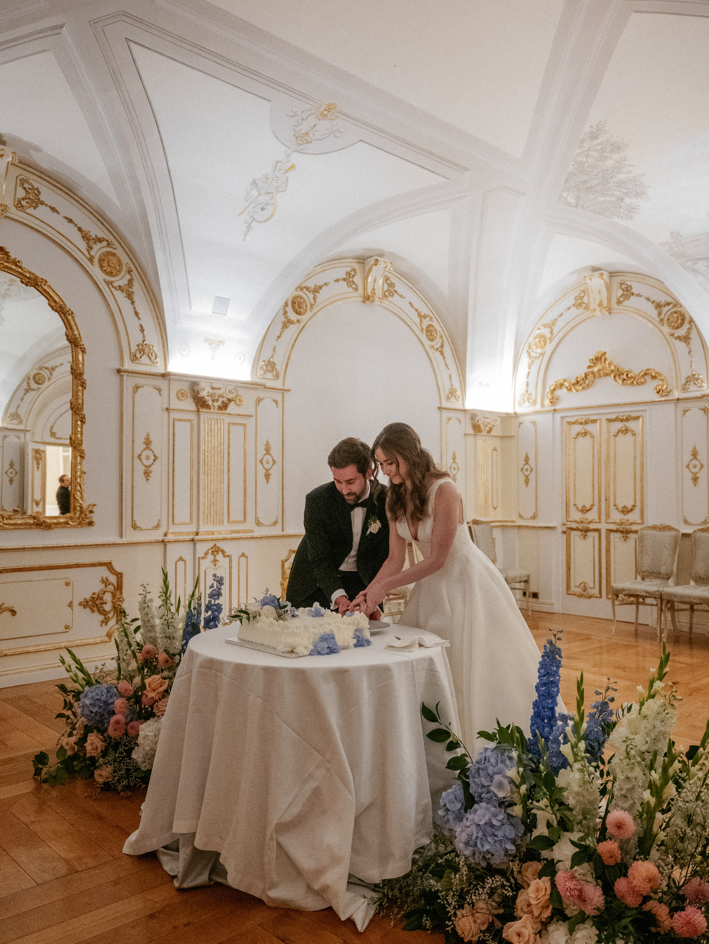 Bride and groom cutting into a millefoglie with frilly icing and blue hydrangea. 