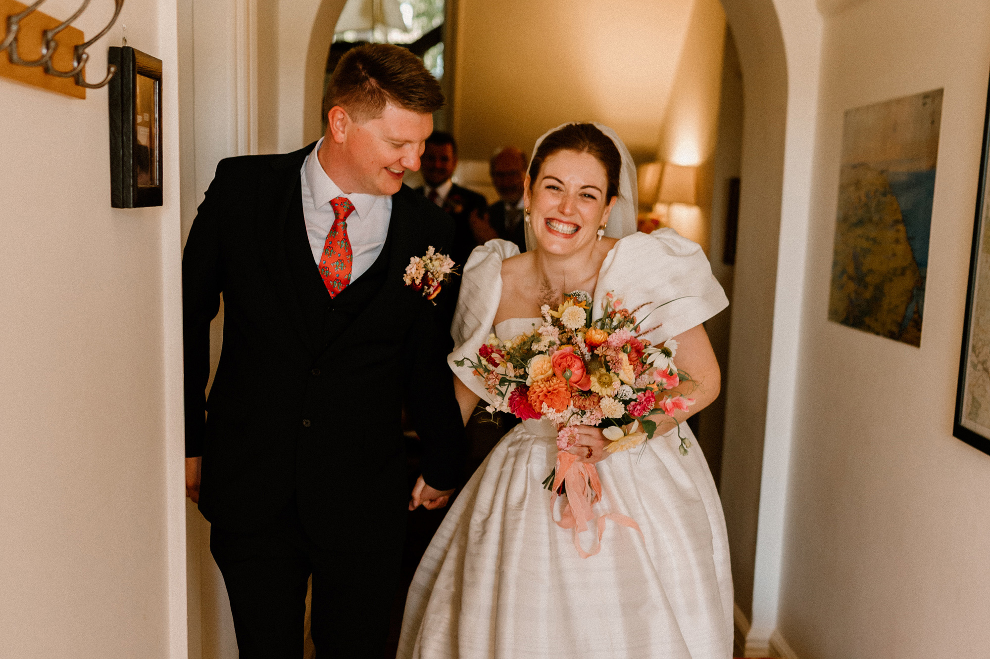 Happy smiling bride wearing a puff sleeve Jesus Peiro dress and carrying a colourful summer wedding bouquet